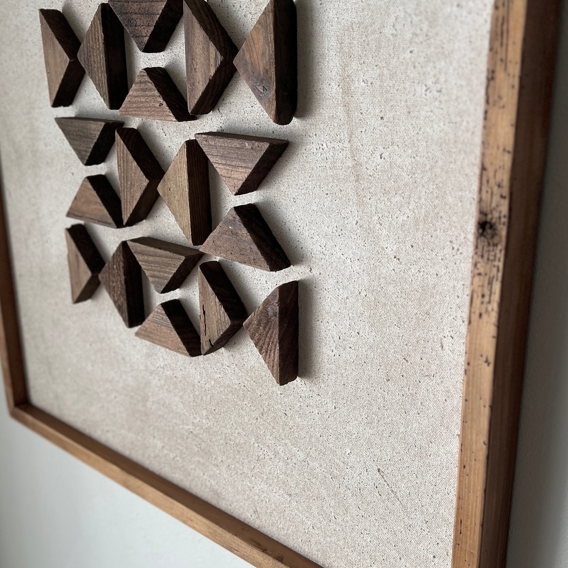三角形の立体的なウッドパーツが幾何学的に貼り付けられたアート