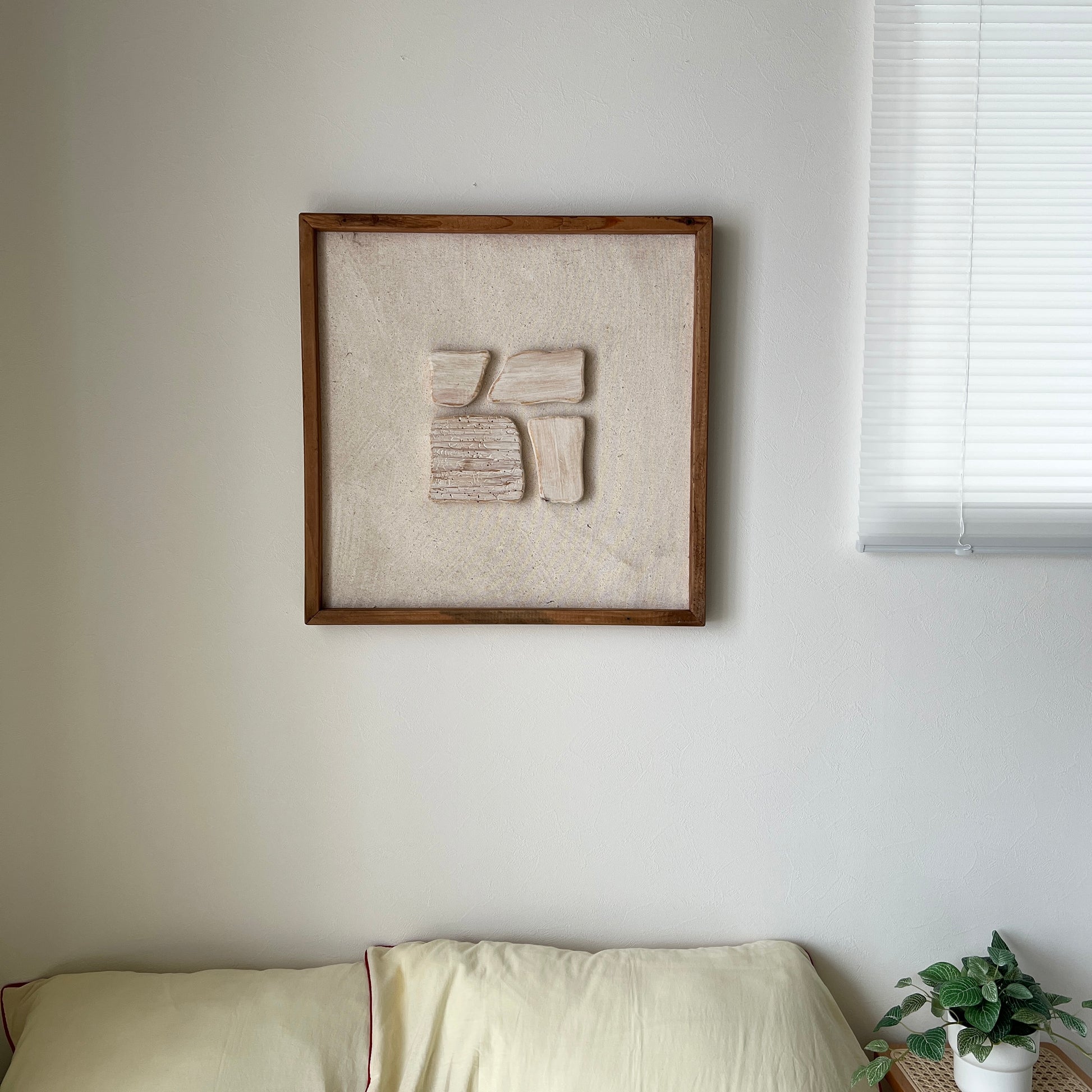 ベージュの立体的なウッドピースが貼り付けられたアートが壁にかかっている様子