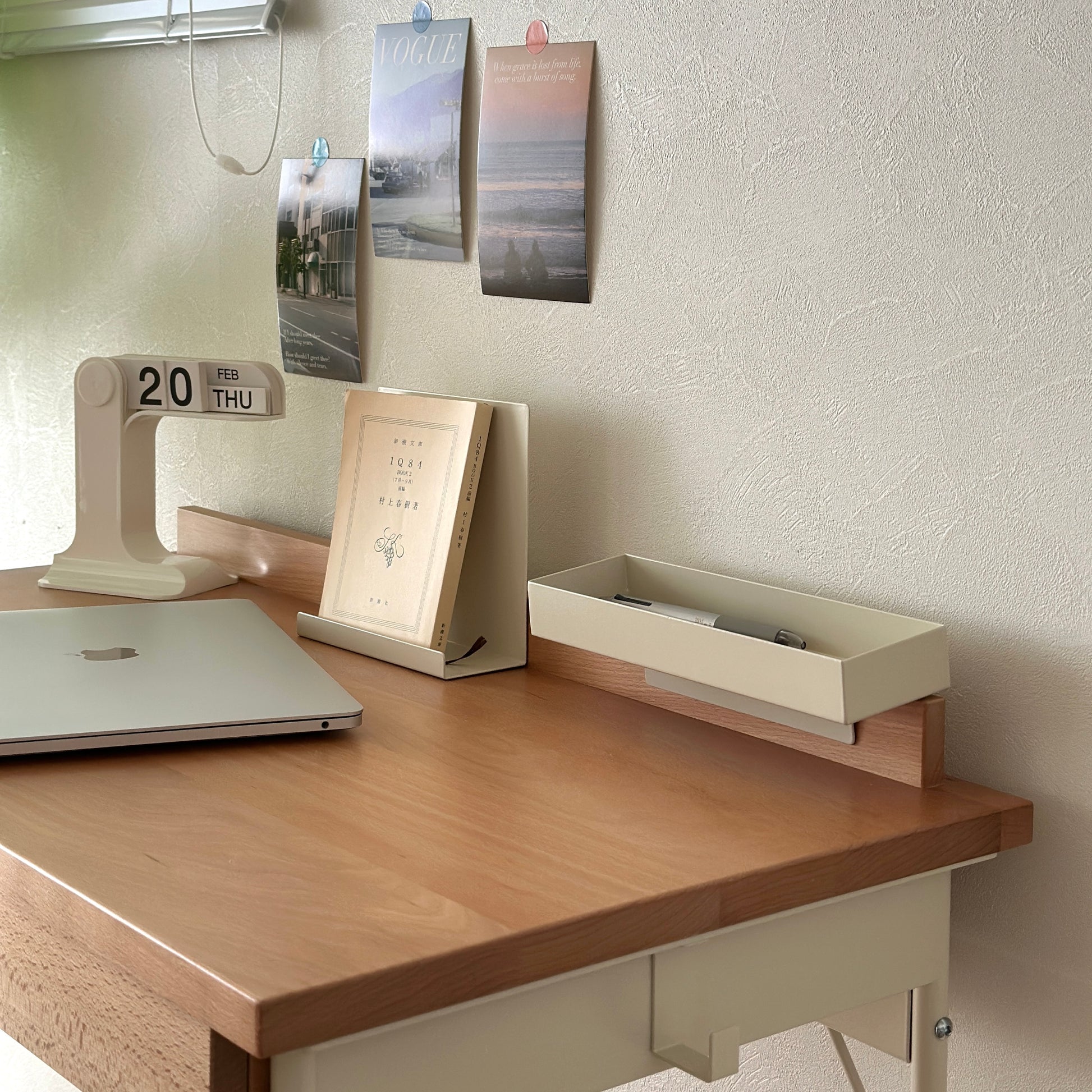 ウッドとスチール素材のデスクに本やカレンダー、パソコンを置いている様子