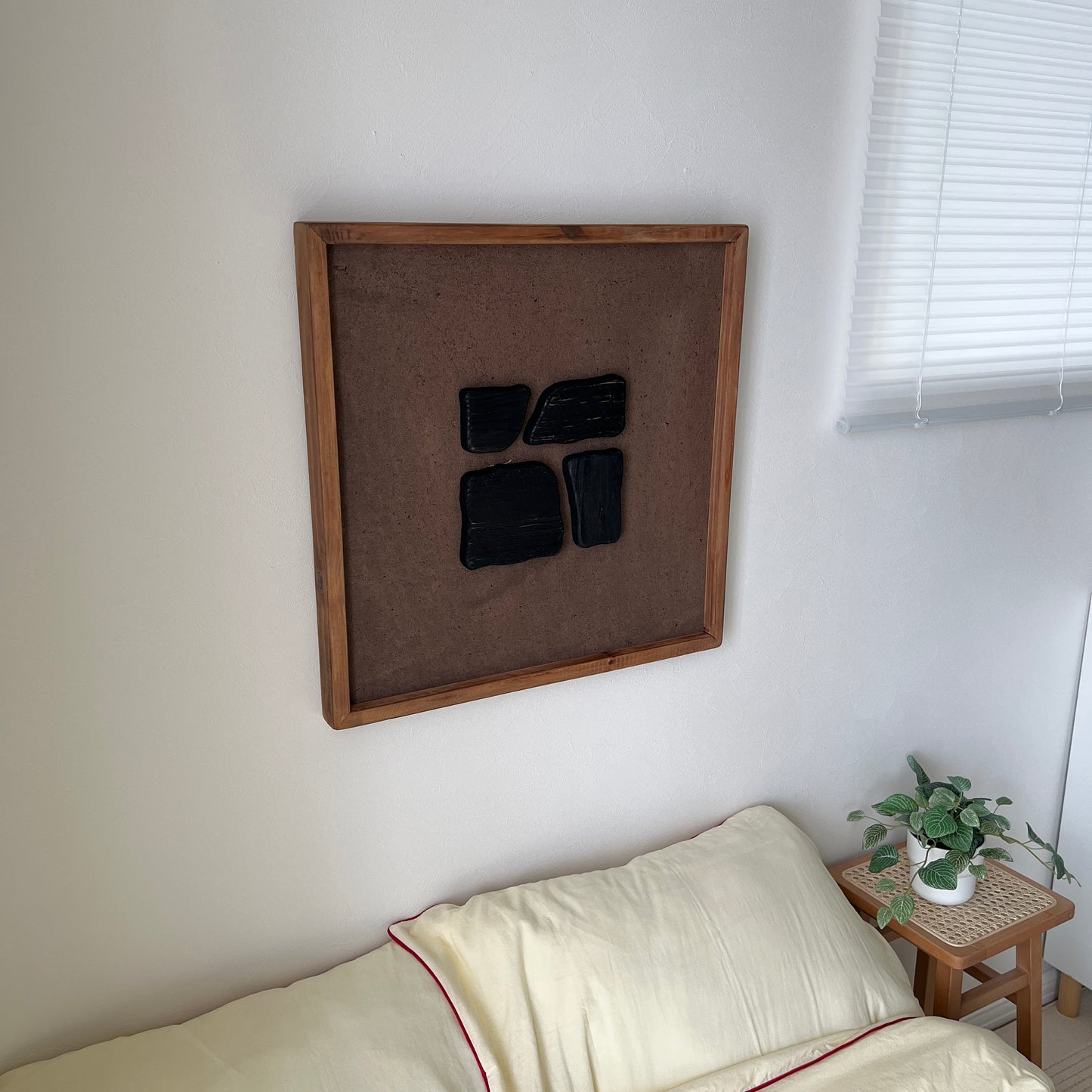 ブラックのウッドピースが立体的に貼り付けられたアートが壁にかかっている様子