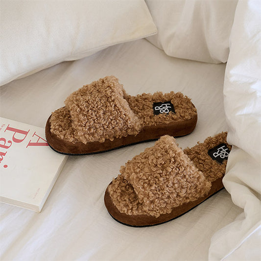 モコモコしたブークレ素材のスリッパがベッドの上に置かれている