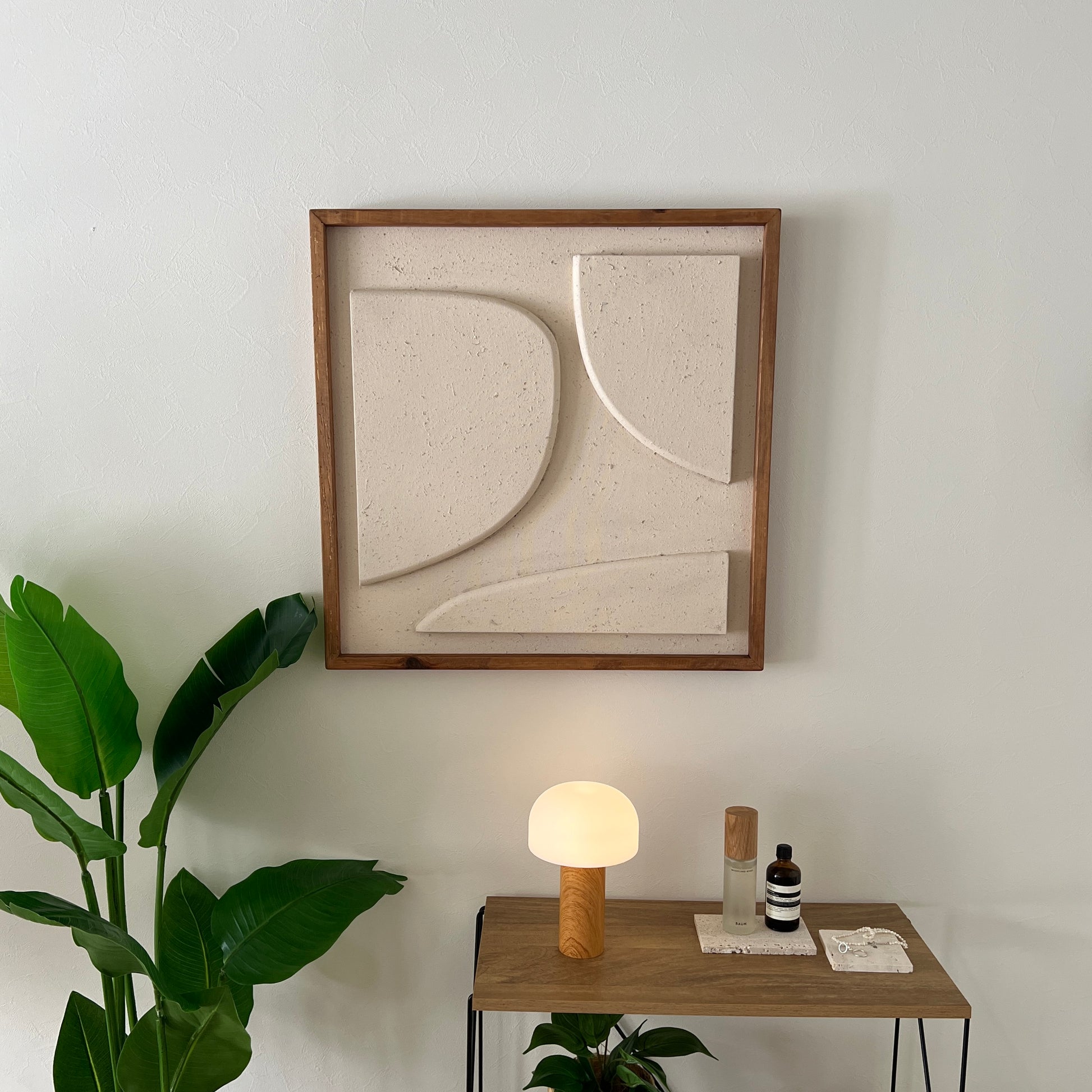 ベージュの立体的なウッドピースが貼り付けられたアートが壁にかかっている様子