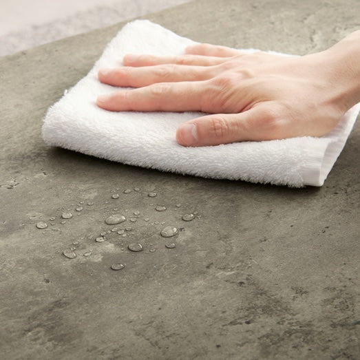 コンクリ風デザインのサイドテーブルの天板に付いた水滴を吹いている様子