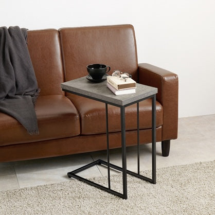 リビングにコンクリ風デザインのサイドテーブルとブラウンの革製ソファが置いてある部屋の様子