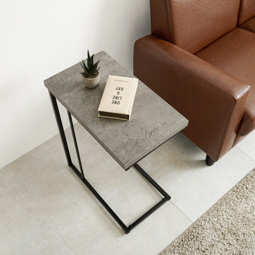 リビングにコンクリ風デザインのサイドテーブルとブラウンの革製ソファが置いてある部屋の様子