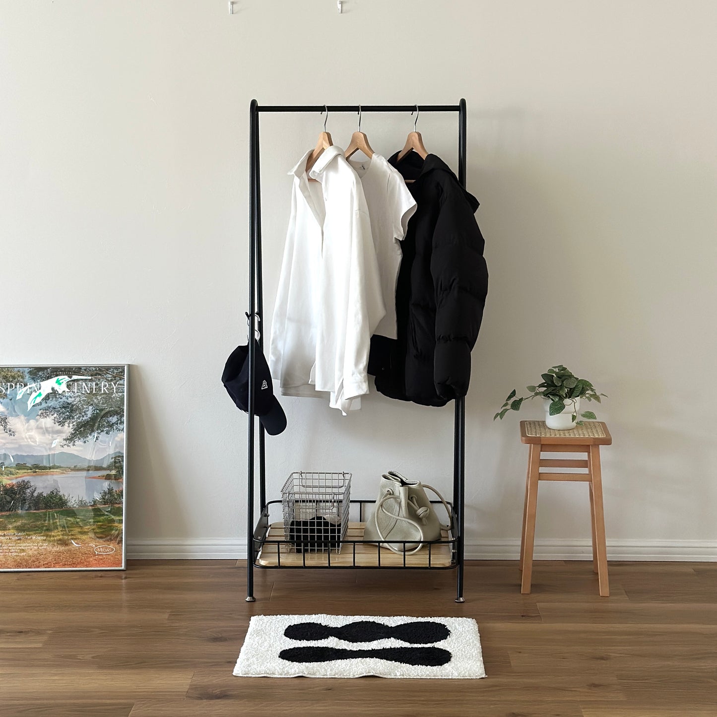 ブラックのスチール製のハンガーラックに洋服や帽子が掛けられている様子