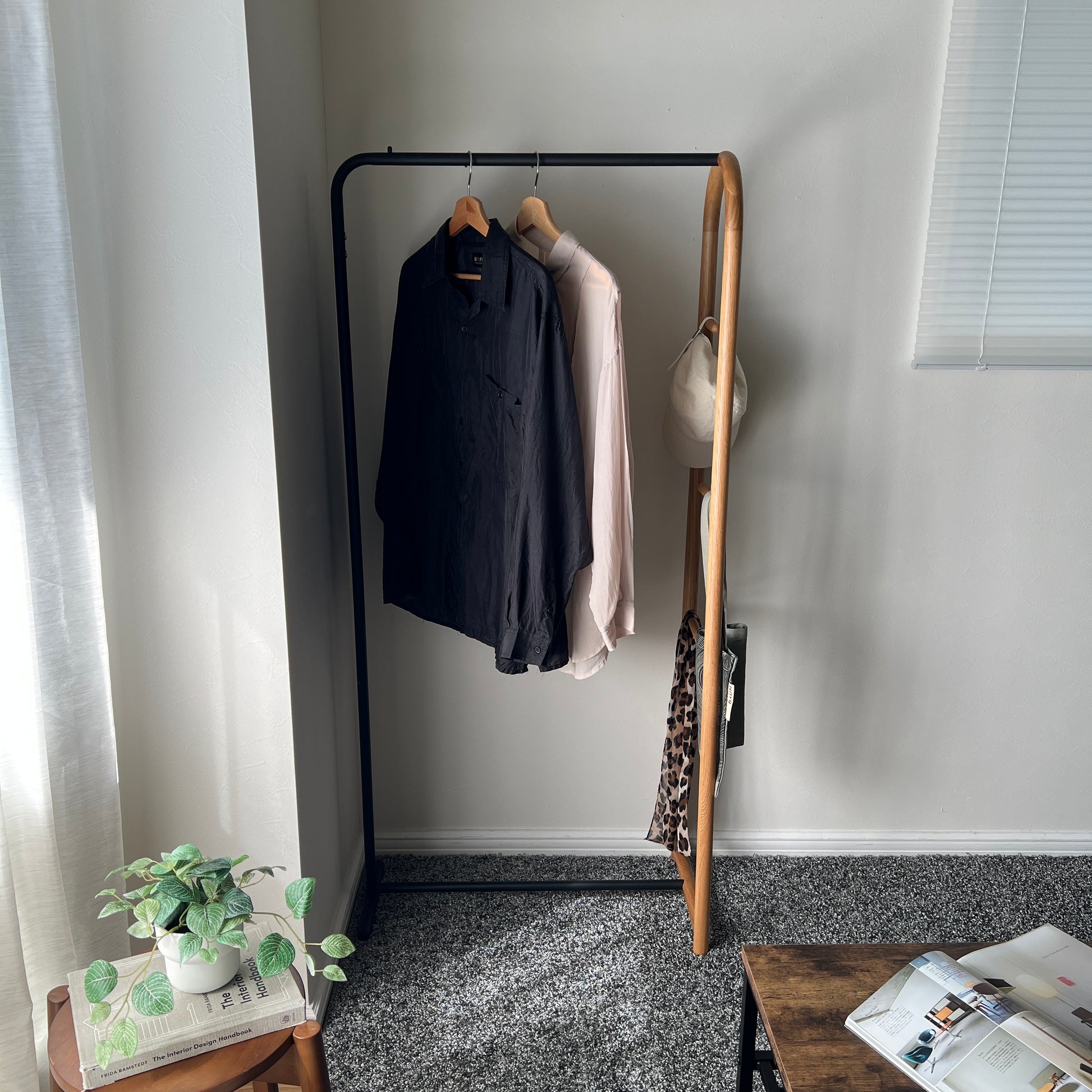 オーク材とブラックスチールのハンガーラックを部屋の隅に置いている様子