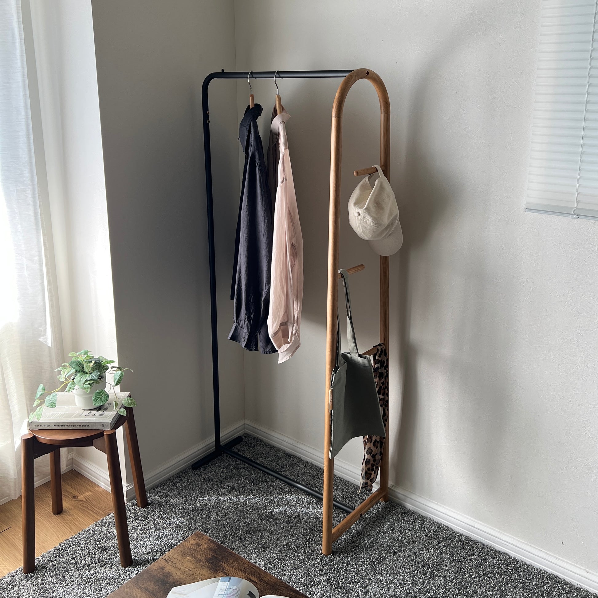 オーク材とブラックスチールのハンガーラックを部屋の隅に置いている様子