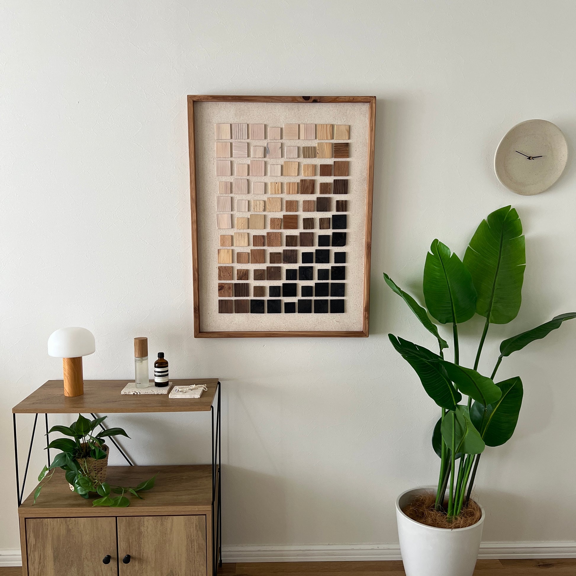 ウッドチップが立体的に貼り付けられたアートが部屋の壁にかかっている様子