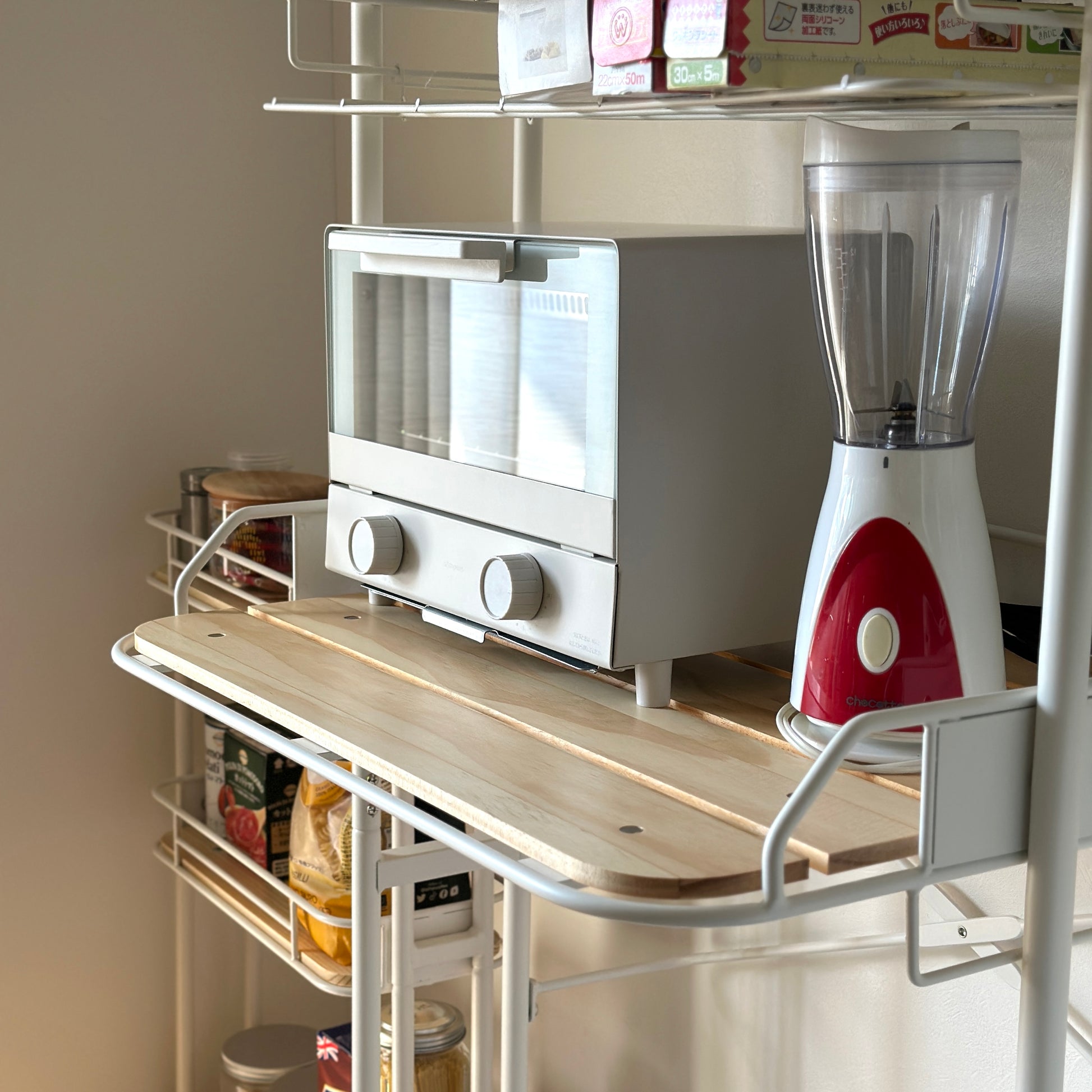 ホワイトとウッドのキッチンラックにキッチン用品が置かれている様子