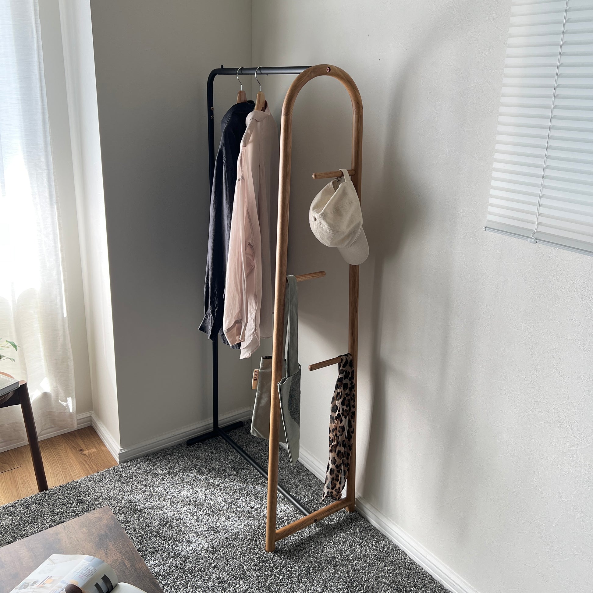オーク材とブラックスチールのハンガーラックを部屋の隅に置いている様子