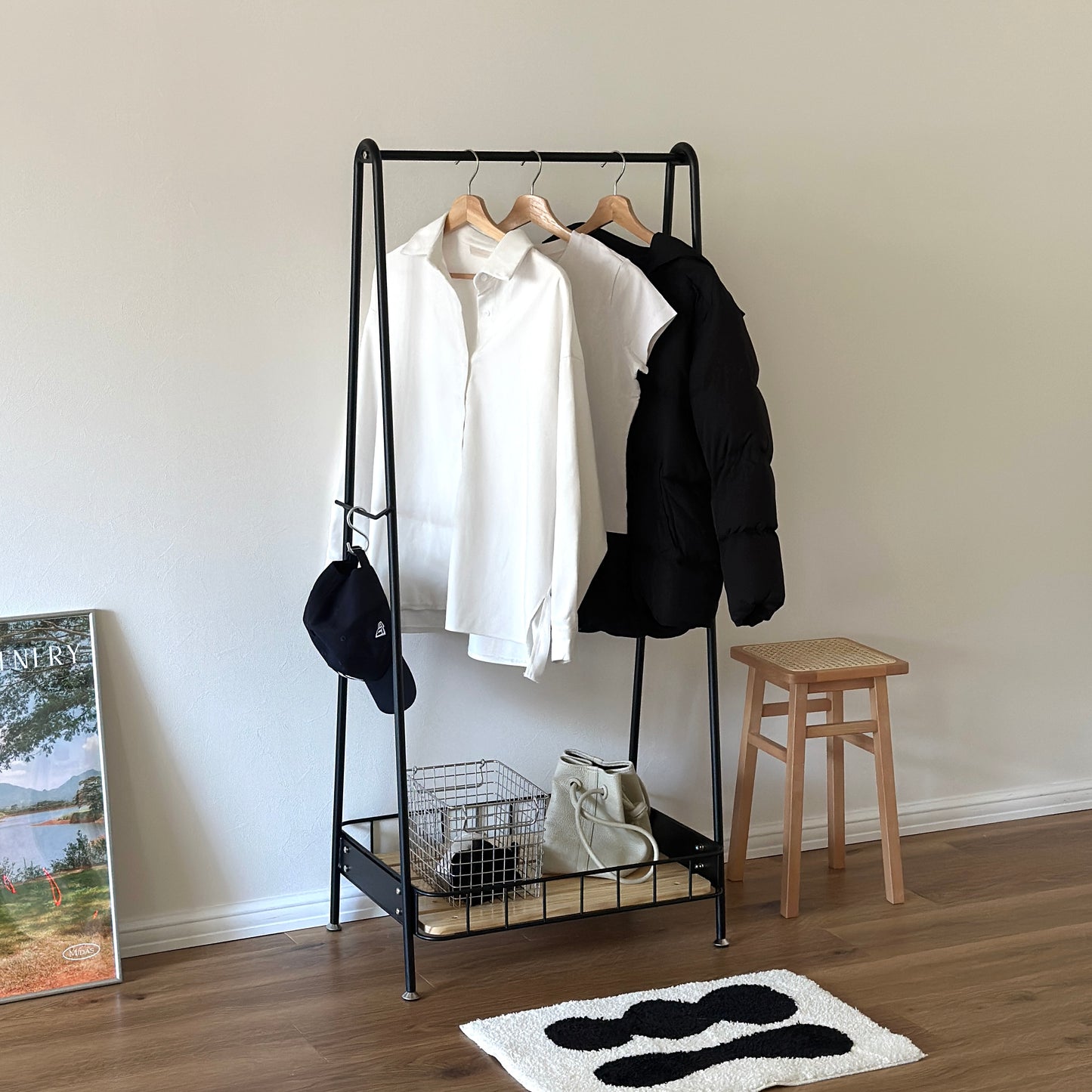 ブラックのスチール製のハンガーラックに洋服や帽子が掛けられている様子