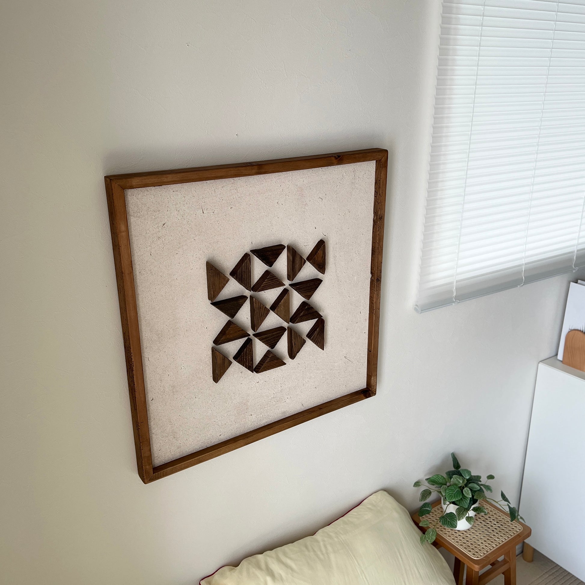 三角形の立体的なウッドパーツが幾何学的に貼り付けられたアート