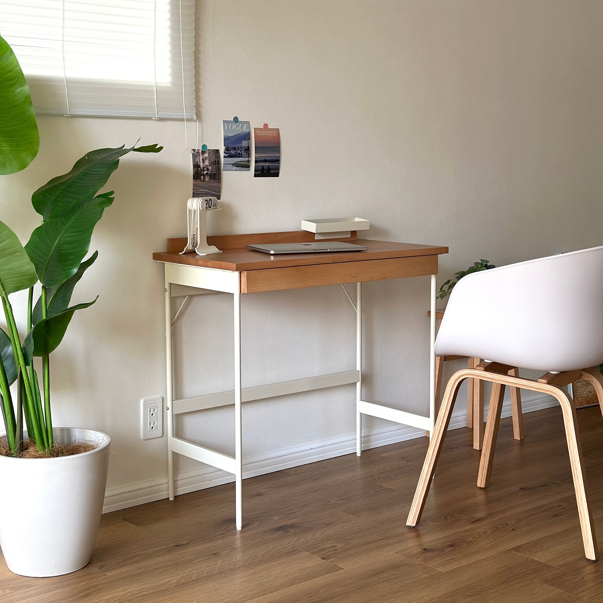 ウッドとスチール素材のデスクにカレンダーと本とパソコンを置いている様子