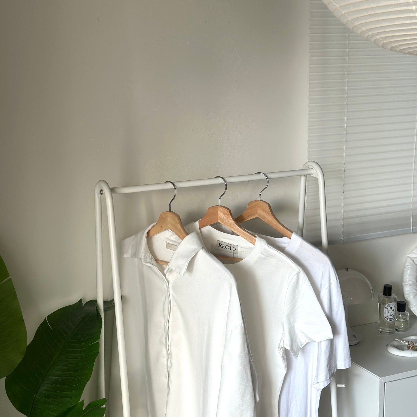 ホワイトのスチール製のハンガーラックに洋服が掛けられている様子