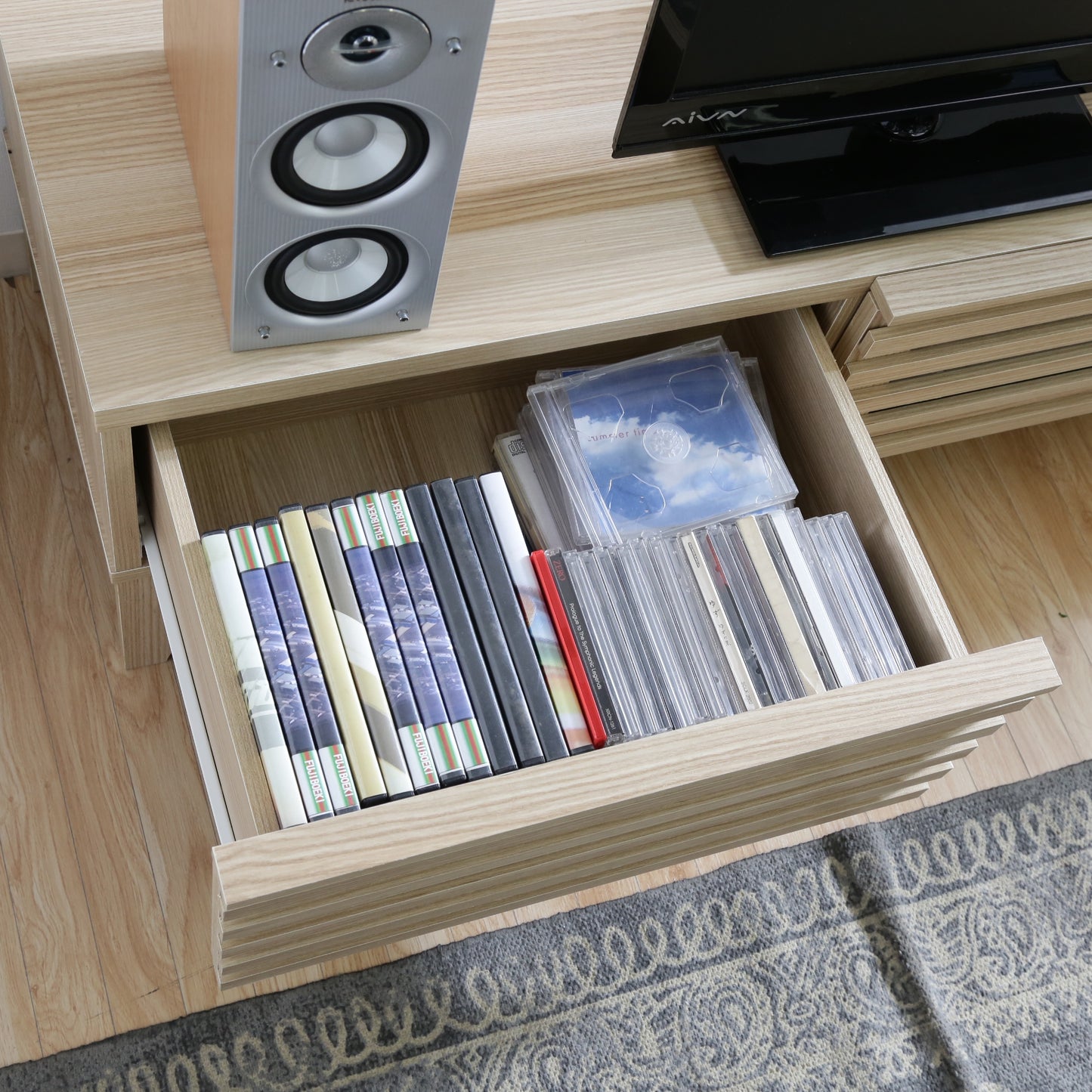 ナチュラルウッドのテレビボードの引き出し収納にDVDやCDが入ってある