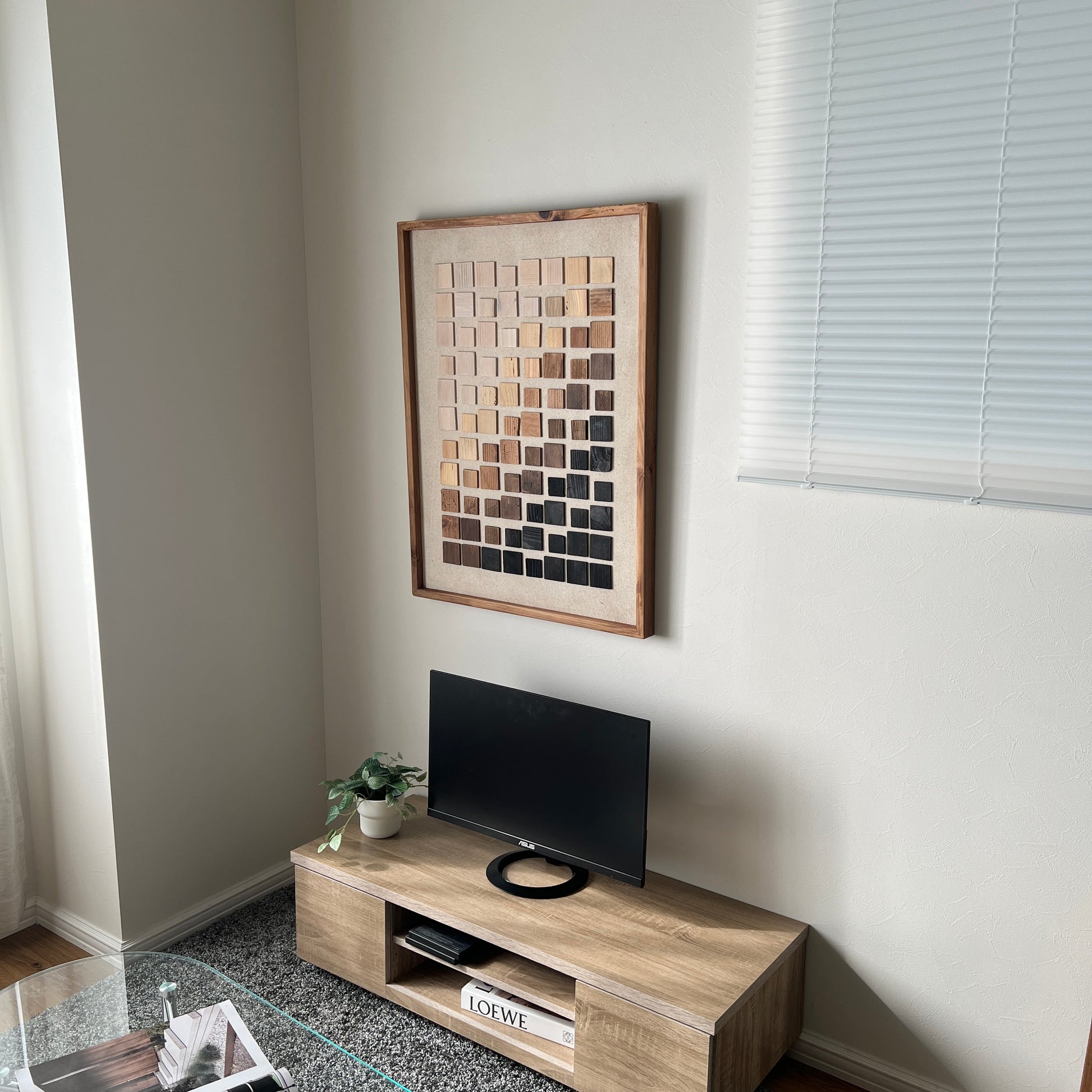 ウッドチップが立体的に貼り付けられたアートが部屋の壁にかかっている様子