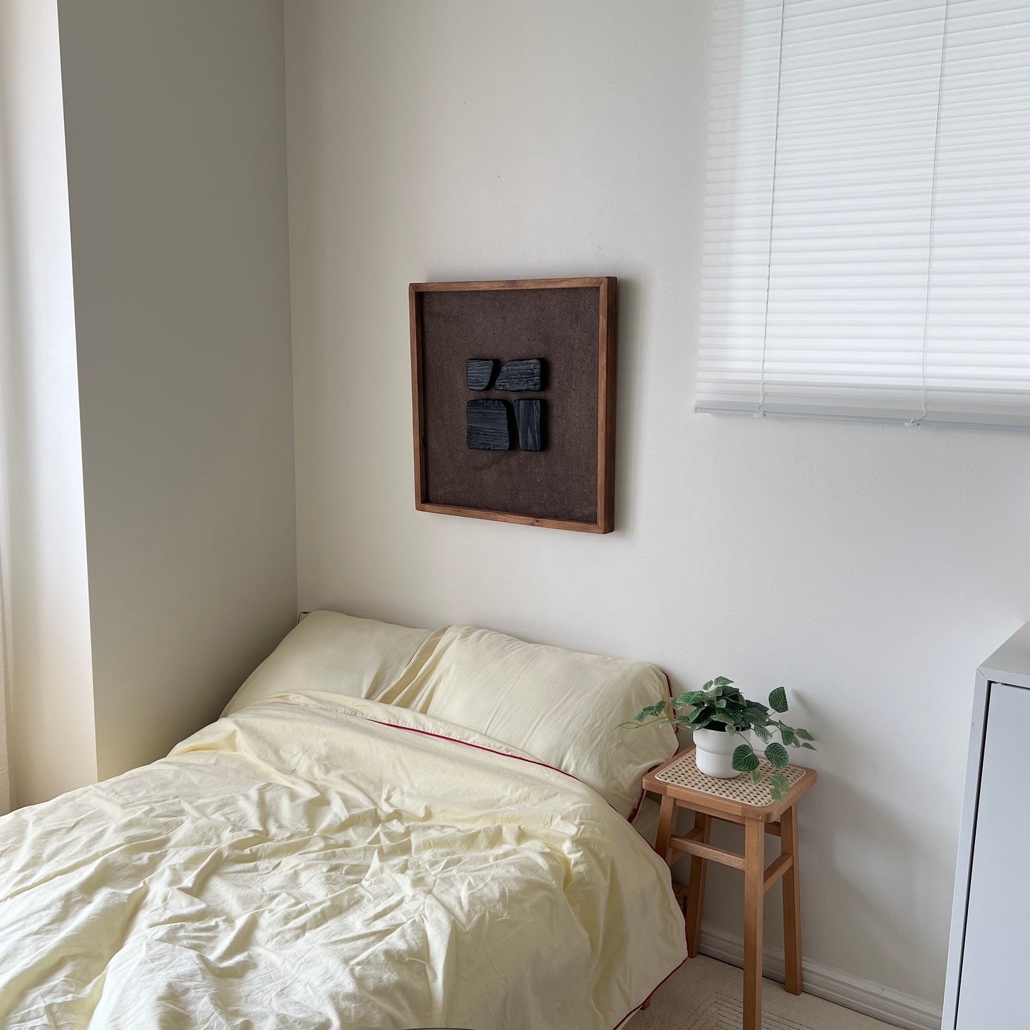 ブラックのウッドピースが立体的に貼り付けられたアートが壁にかかっている様子