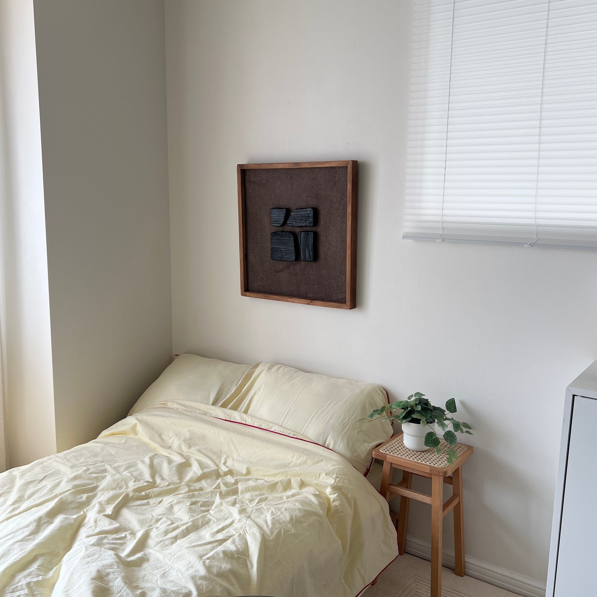 ブラックのウッドピースが立体的に貼り付けられたアートが壁にかかっている様子