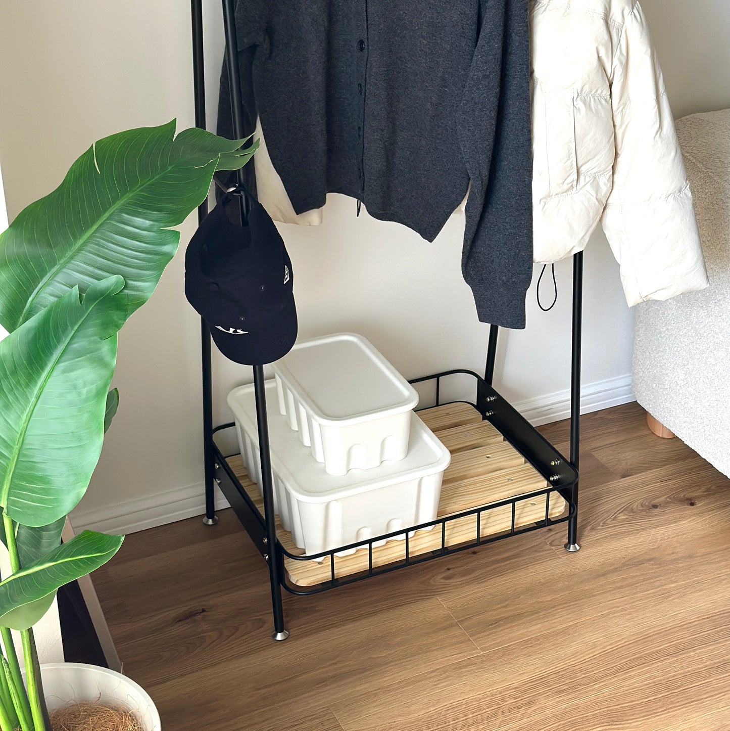 ブラックのスチール製のハンガーラックに洋服や帽子が掛けられている様子