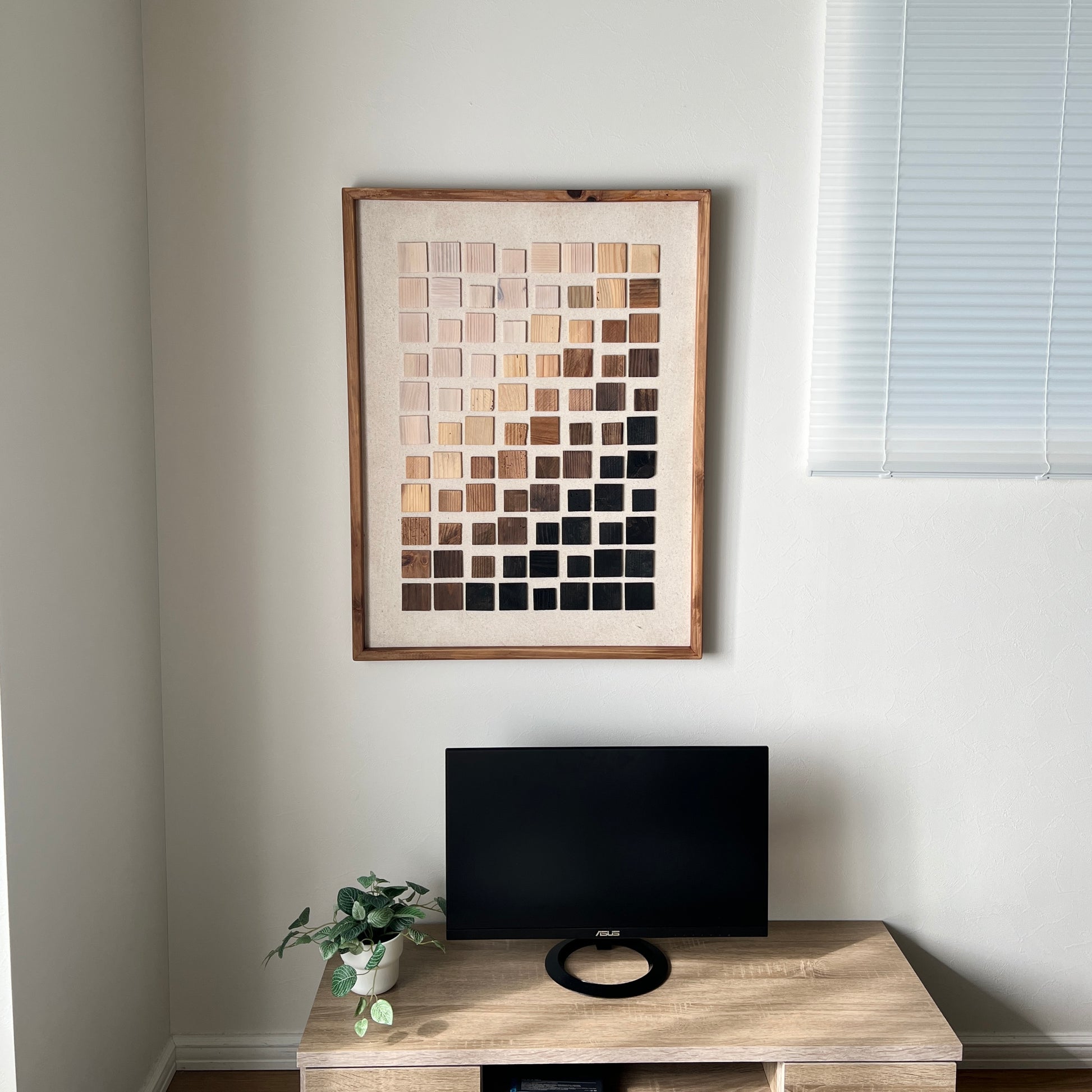 ウッドチップが立体的に貼り付けられたアートが壁にかかっている様子