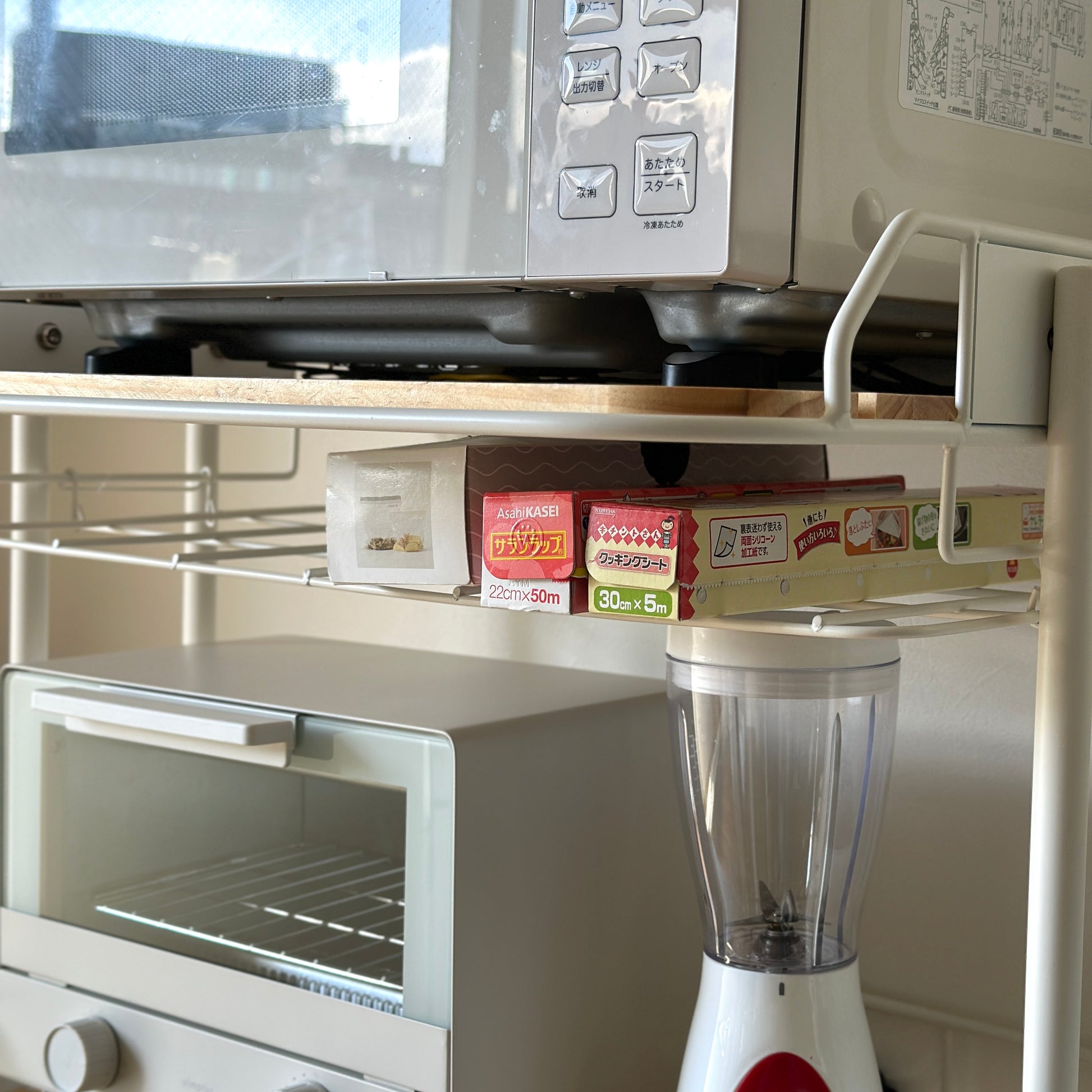 ホワイトとウッドのキッチンラックにキッチン用品が置かれている様子