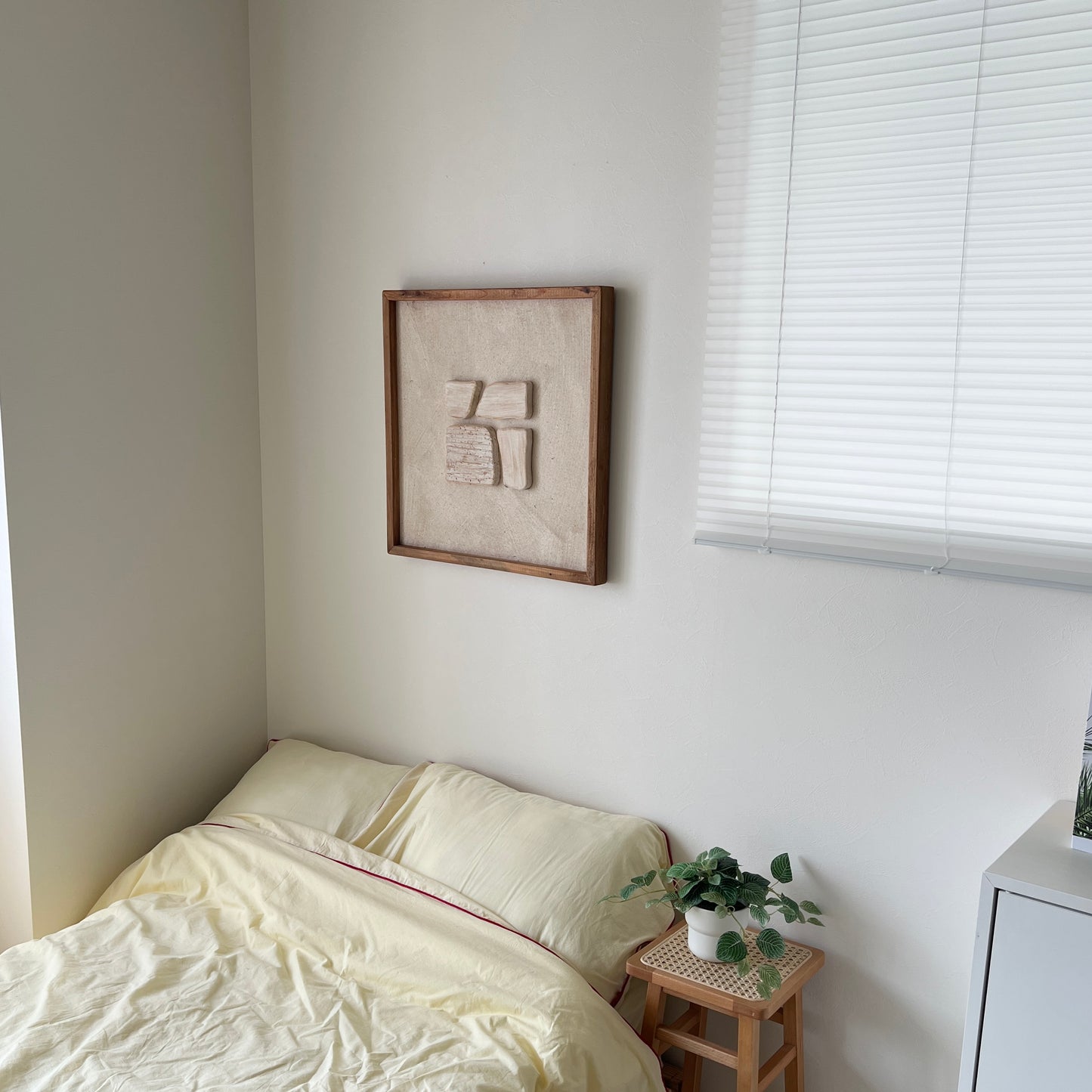 ベージュの立定的なウッドピースが貼り付けられたアートが壁にかかっている様子