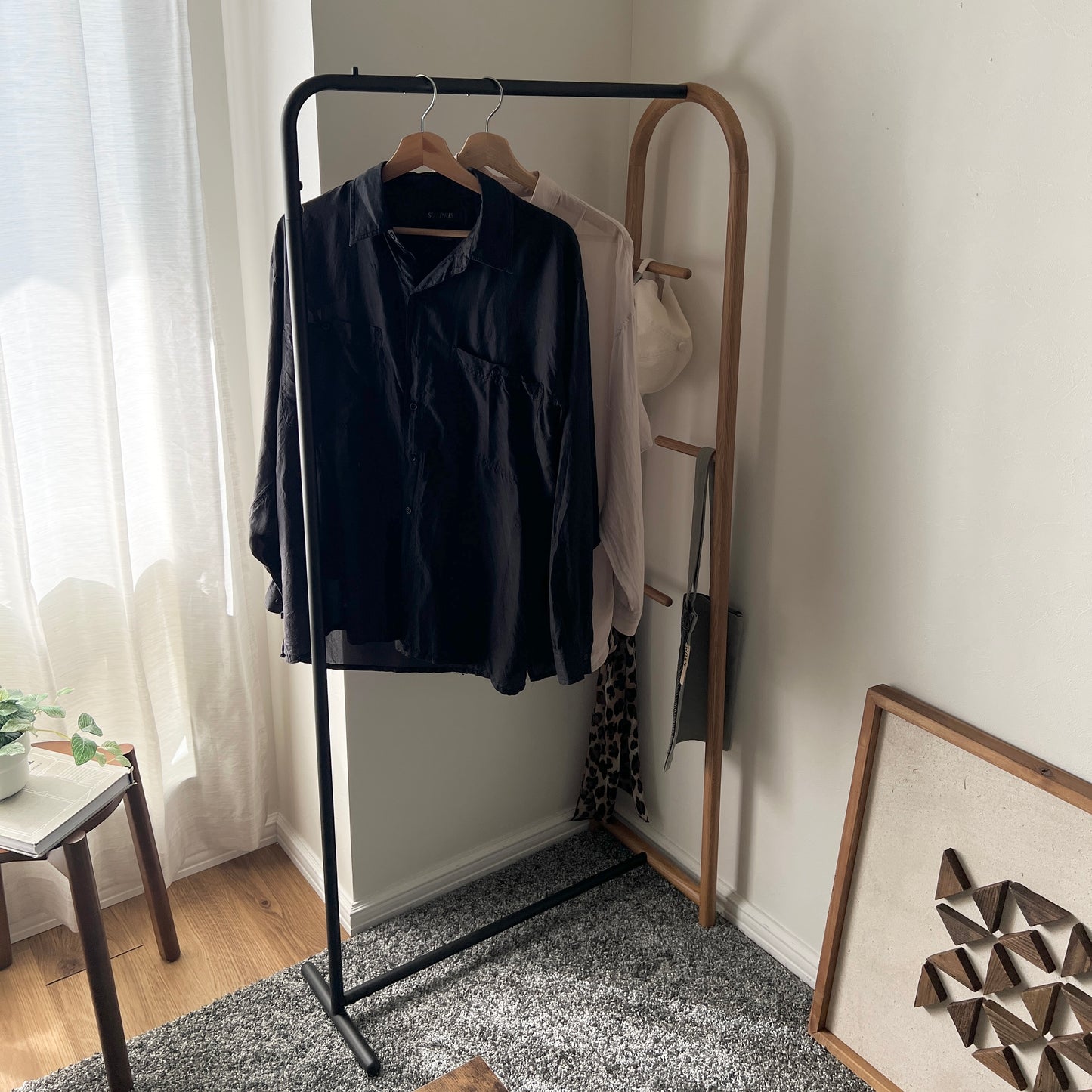 オーク材とブラックスチールのハンガーラックを部屋の隅に置いている様子