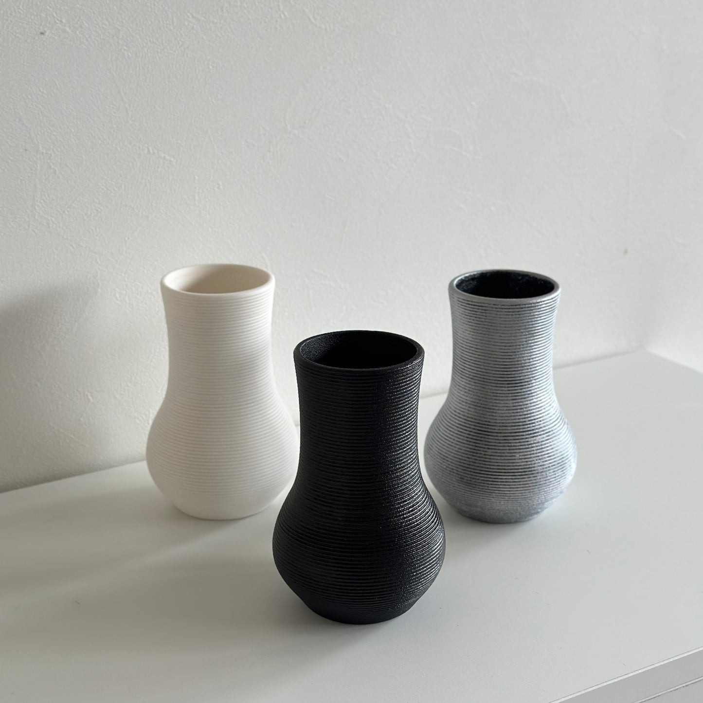 ホワイトとブラックとシルバーの陶器製のフラワーベースが並んで置かれている様子
