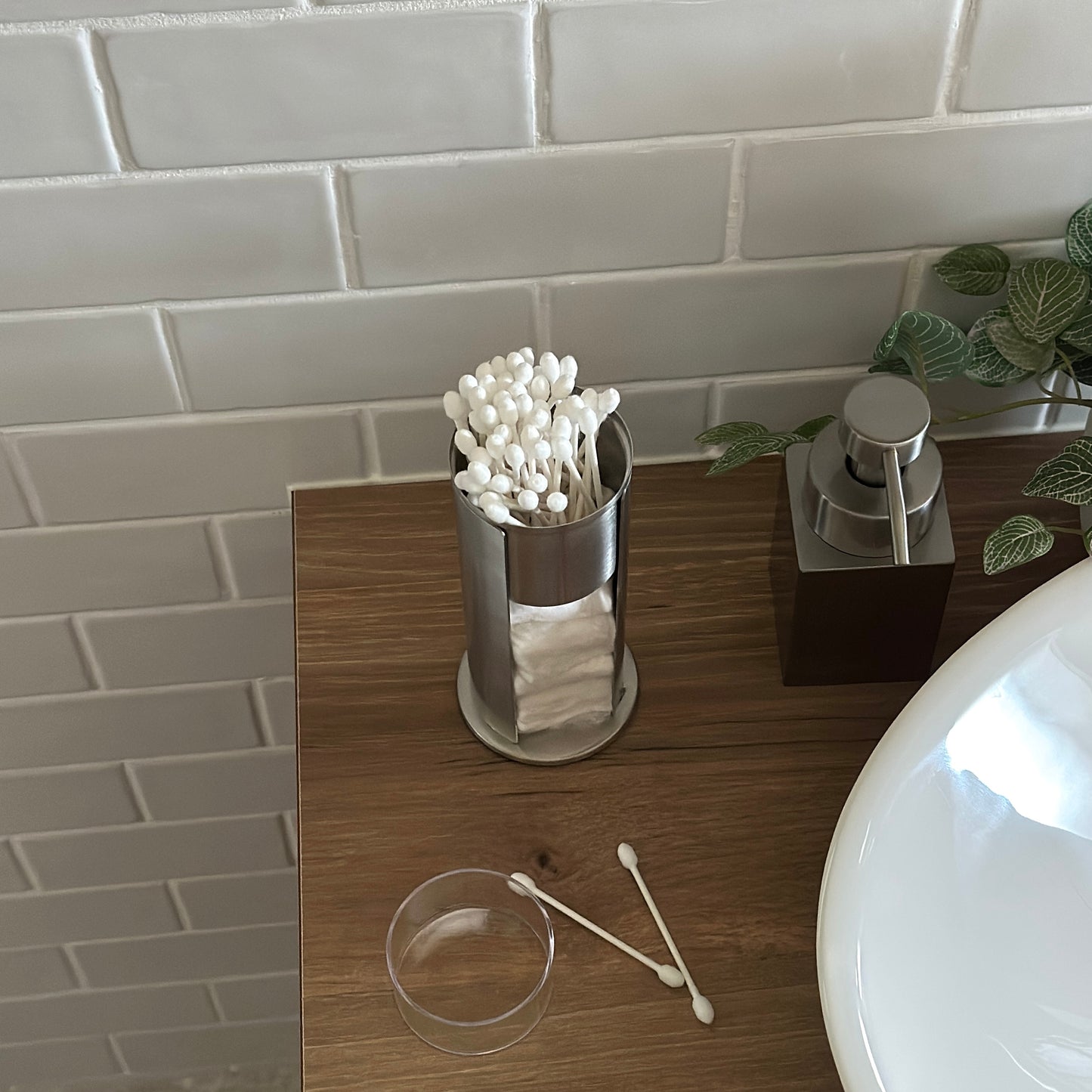 ステンレス素材のコットンと綿棒の縦型収納ケースを洗面台に置いている様子