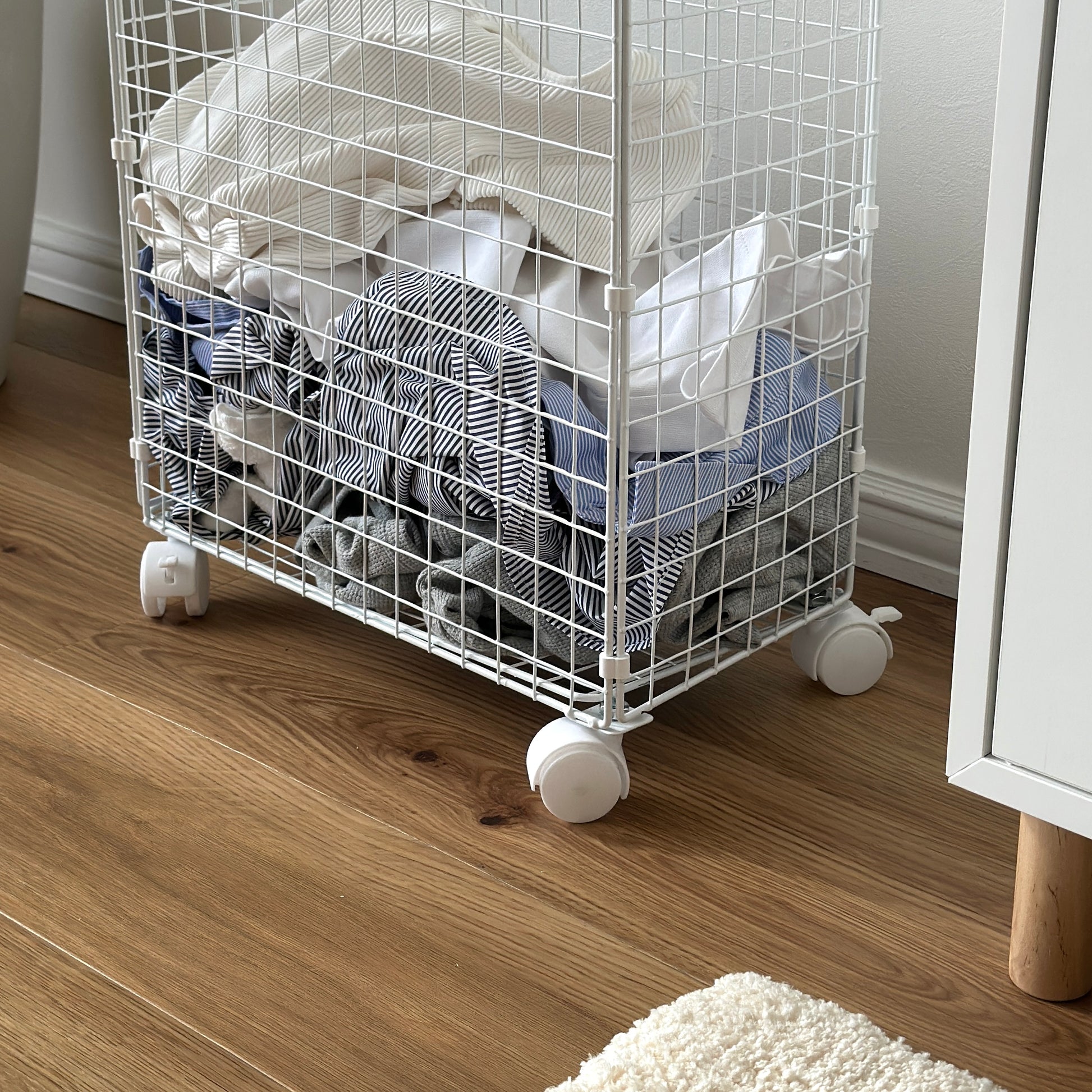ホワイトのメッシュのランドリーワゴンに洋服が入っている様子