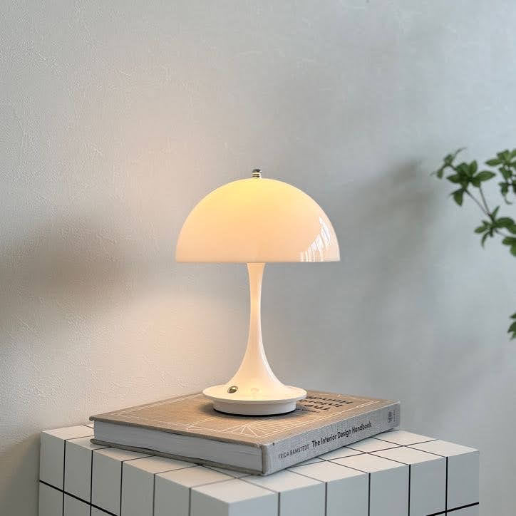 スツールの上に置いたホワイトの大きめのシェードにくびれがかった支柱のデザインのランプが点灯している様子