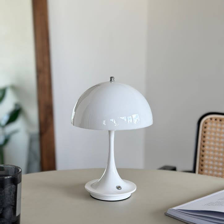 テーブルの上に置いたホワイトの大きめのシェードにくびれがかった支柱のデザインのランプ
