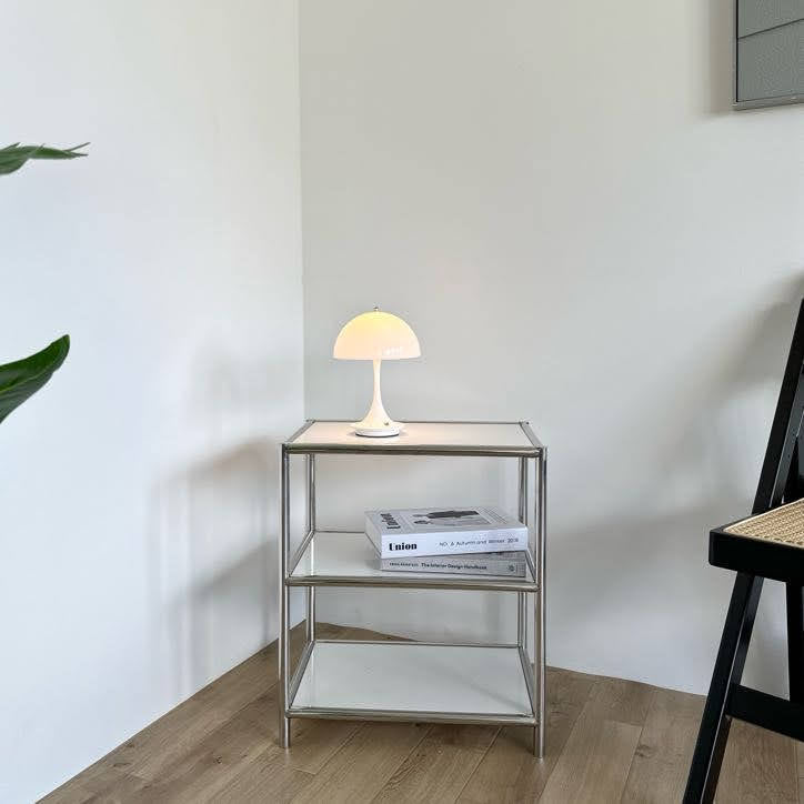 棚の上に置いたホワイトの大きめのシェードにくびれがかった支柱のデザインのランプ