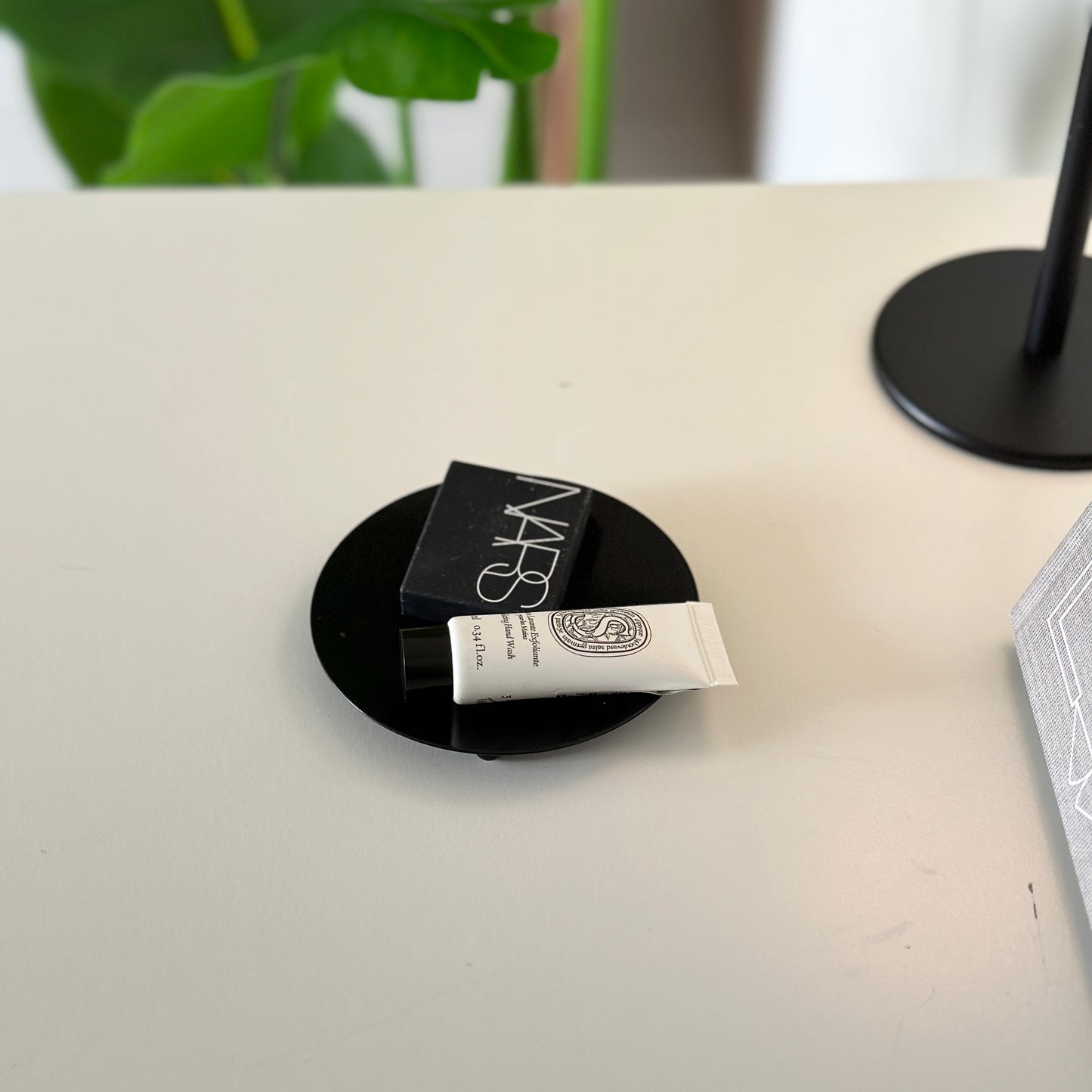 脚付のブラックの鉄製の丸いプレートの上に化粧品が置かれている