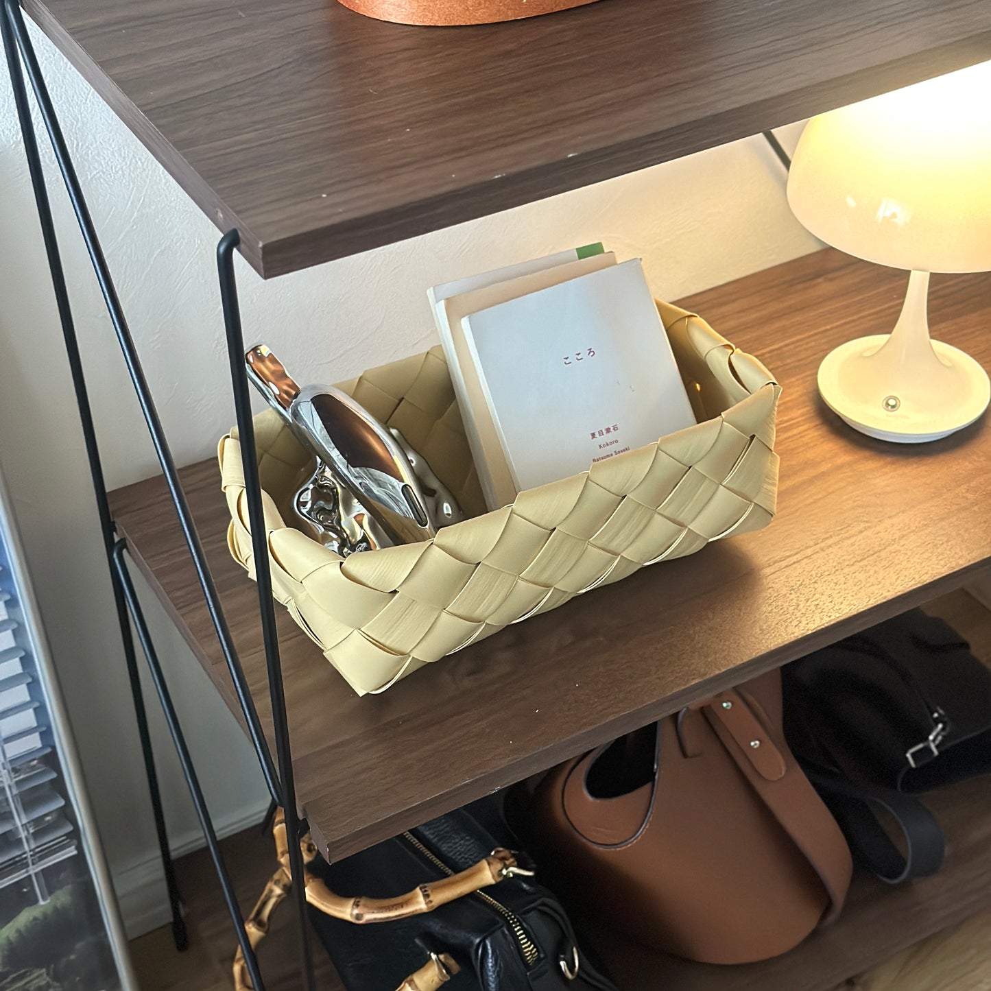 手編みのバスケットに本や小物が収納されている様子