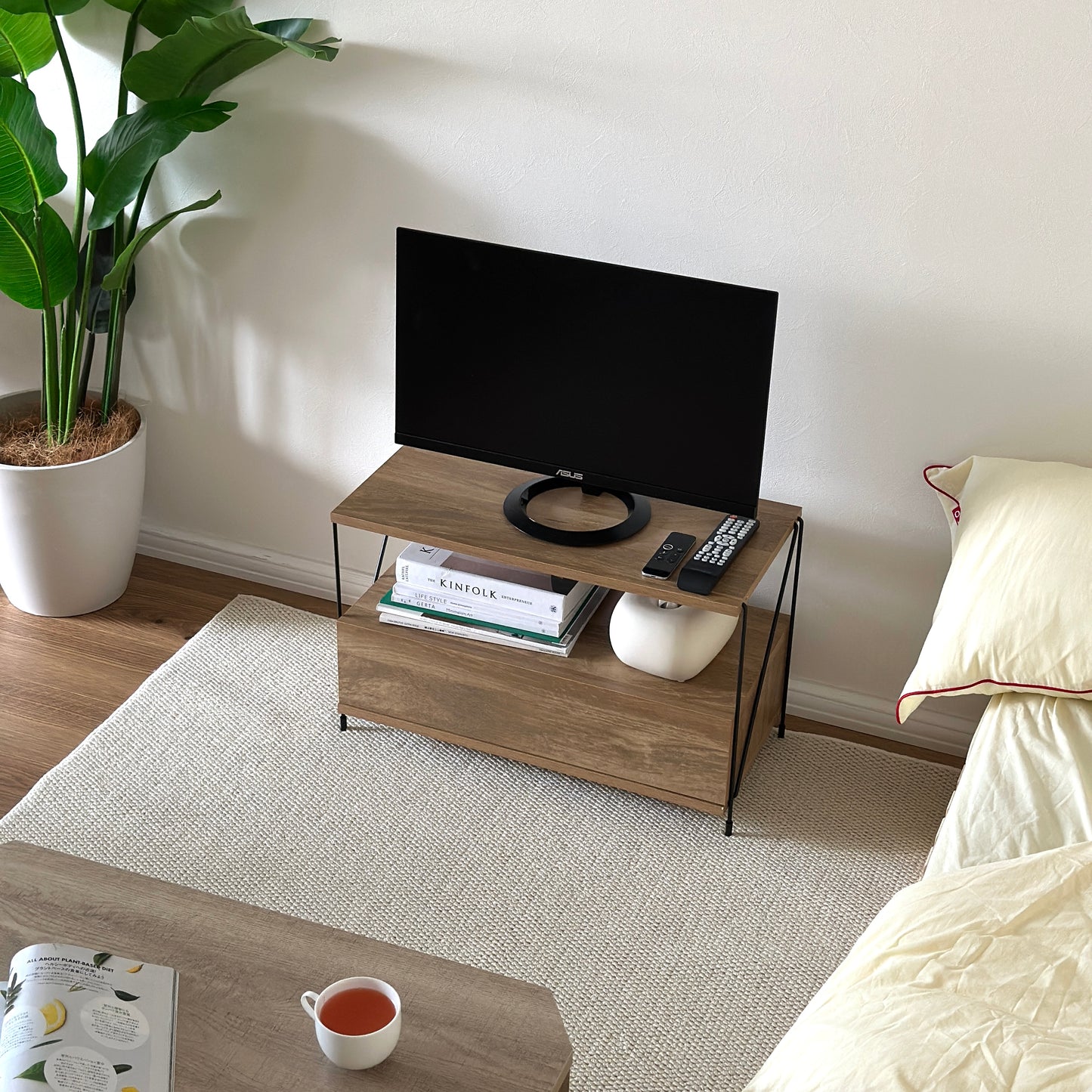 木目のウッドと細いブラックフレームのテレビボードを部屋に置いている様子