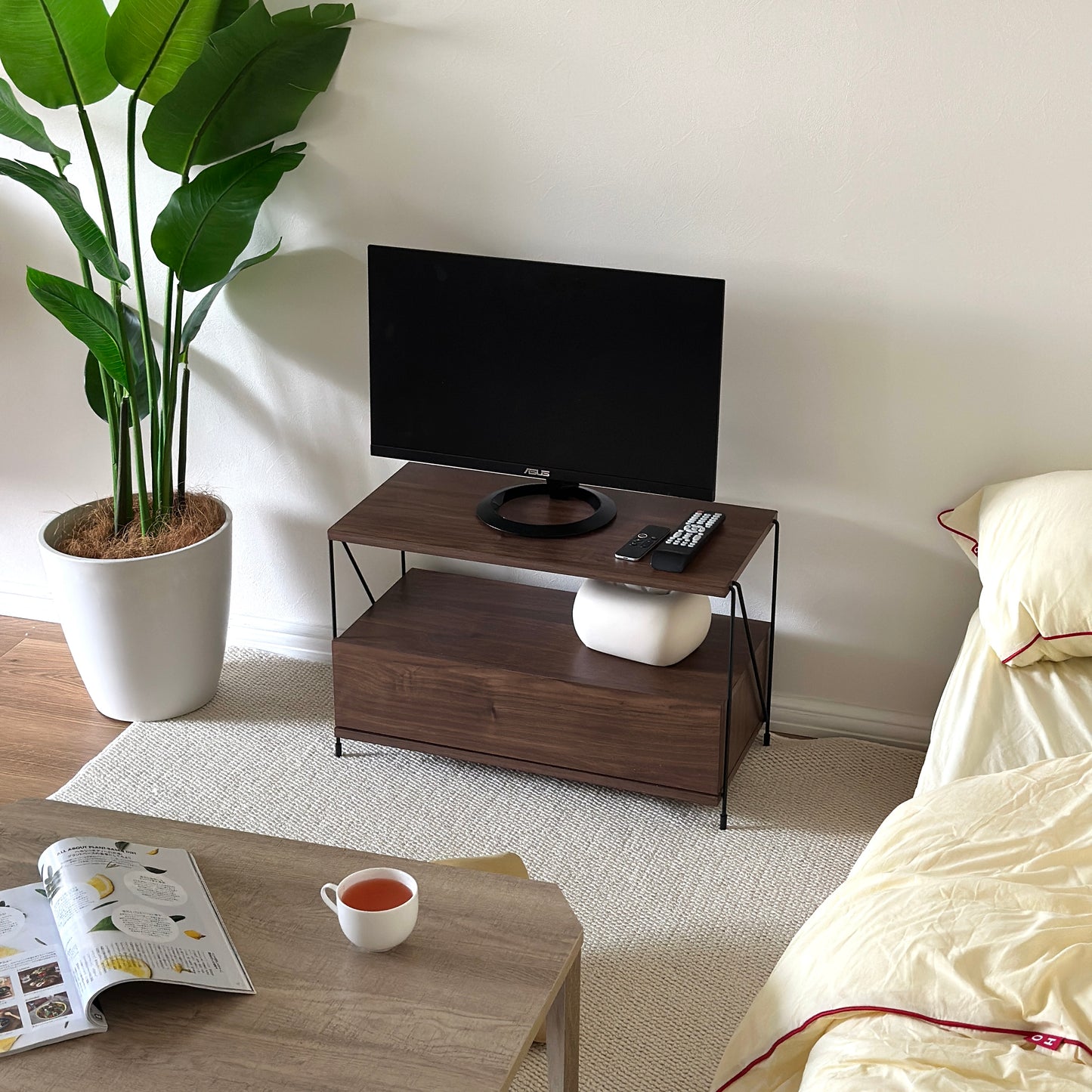木目のウッドと細いブラックフレームのテレビボードの天板下にティッシュケースが置かれている様子