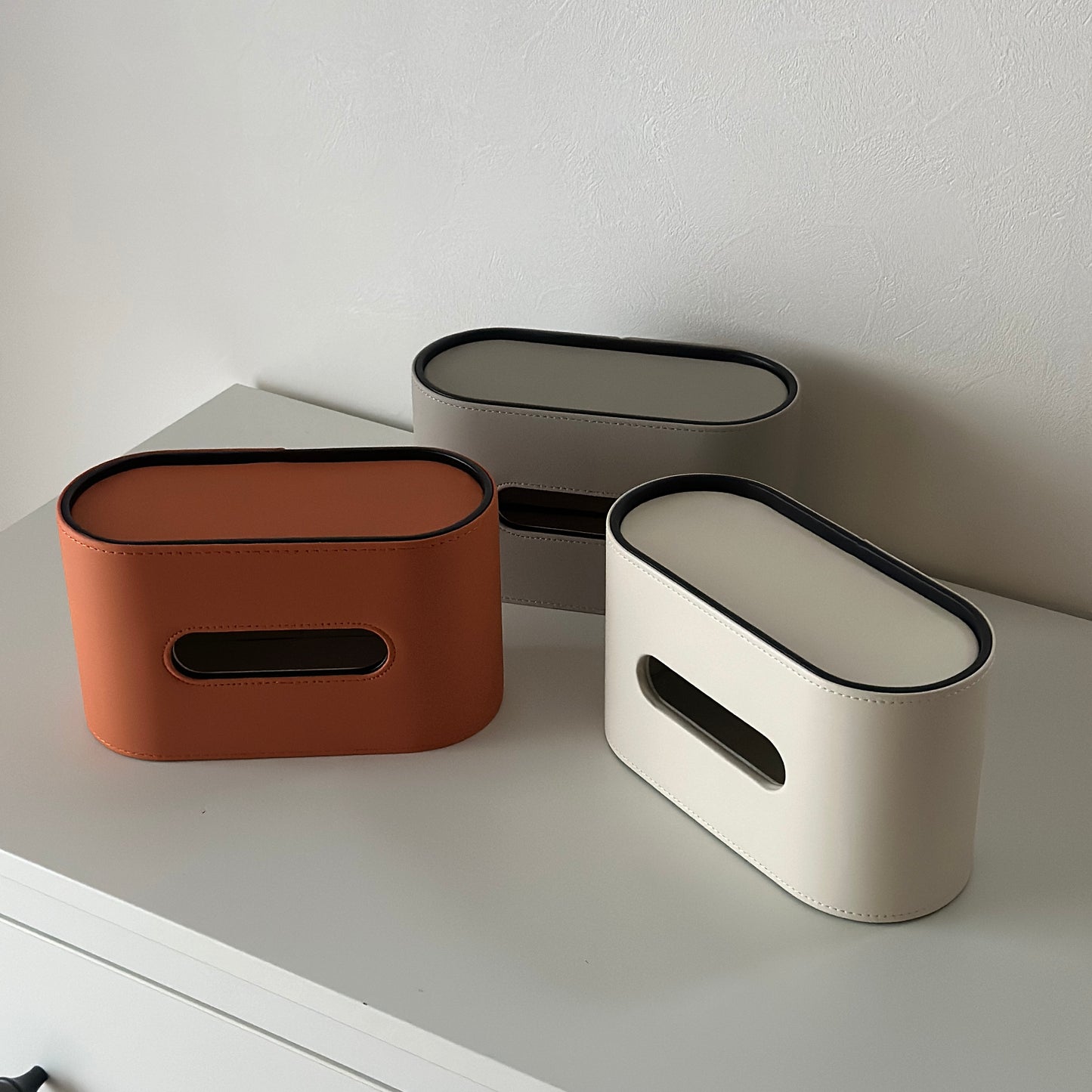 棚の上に置いてあるレザー調デザインの楕円型ティッシュケース3種類