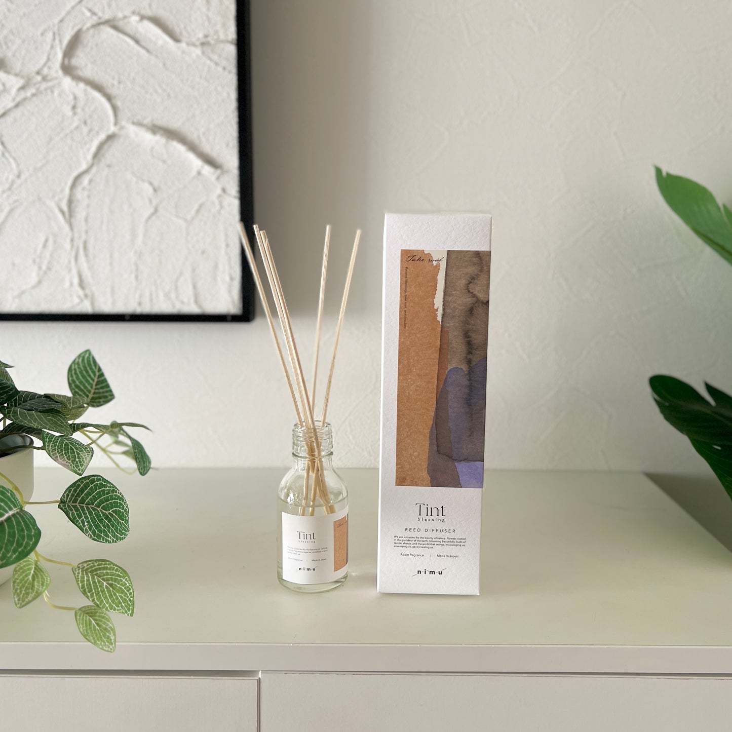 部屋の中の白い棚の上にリードディフューザーのとそのパッケージ箱が並んで飾られている様子