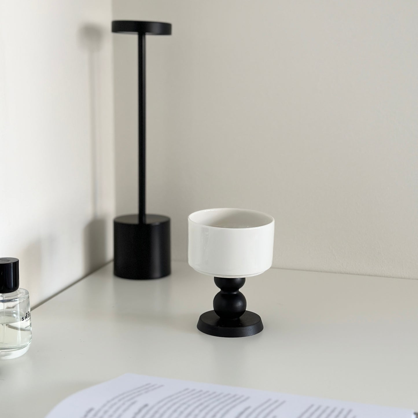 白い机の上に陶器の器に黒いウッド脚が付いたボウルが置かれてある。