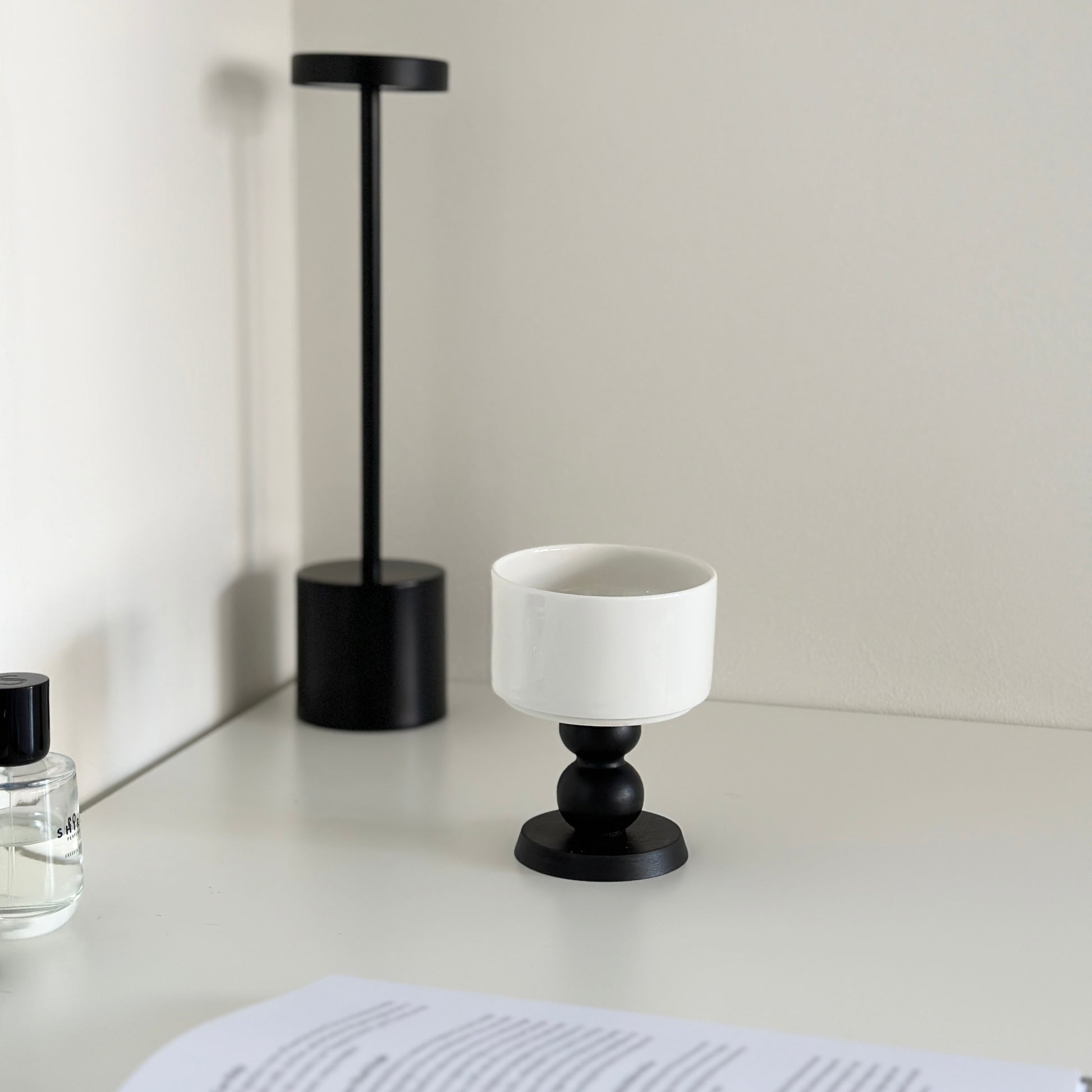 白い机の上に陶器の器に黒いウッド脚が付いたボウルが置かれてある。