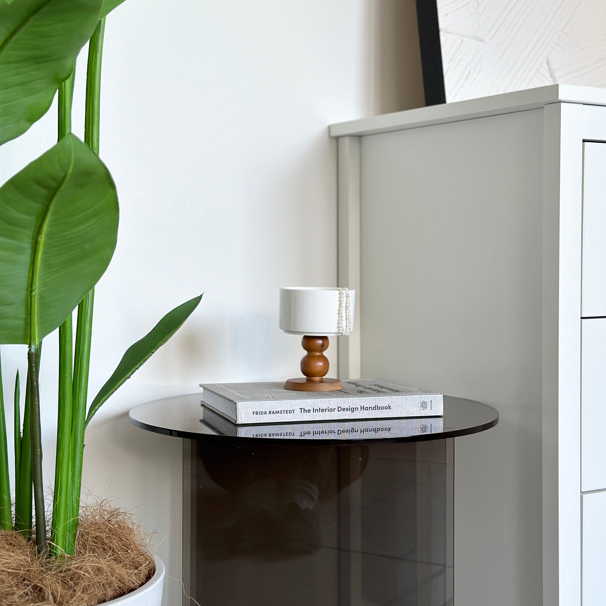 スツールの上に乗せられたブラウンの木製の脚でできた白いボウル