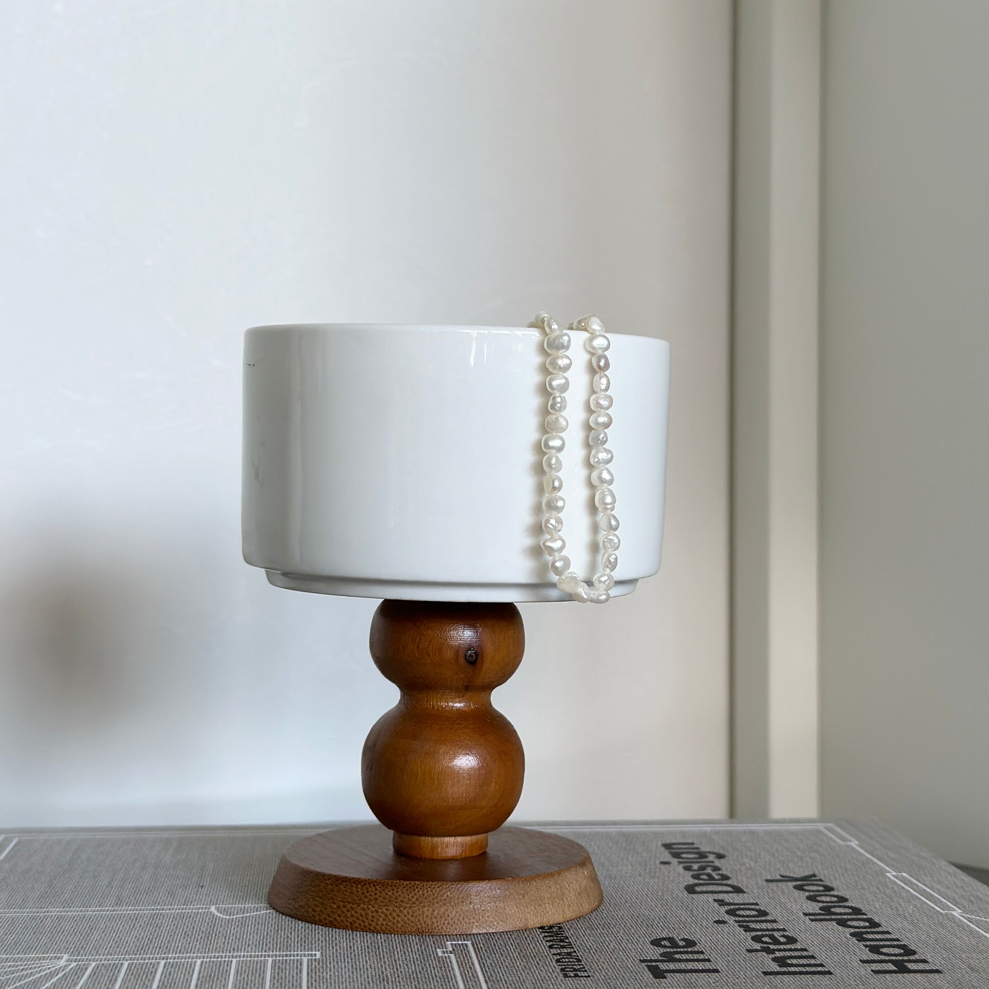 ブラウンの木製の脚でできた白いボウルにアクセサリーが入っている