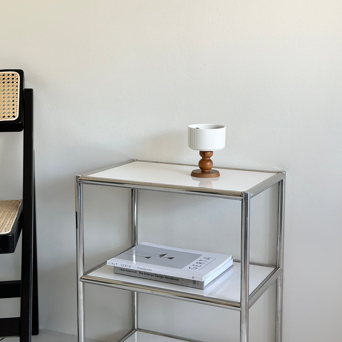 白にフレームがシルバーの棚の上に陶器の器にウッド脚が付いたボウルが置かれてある。