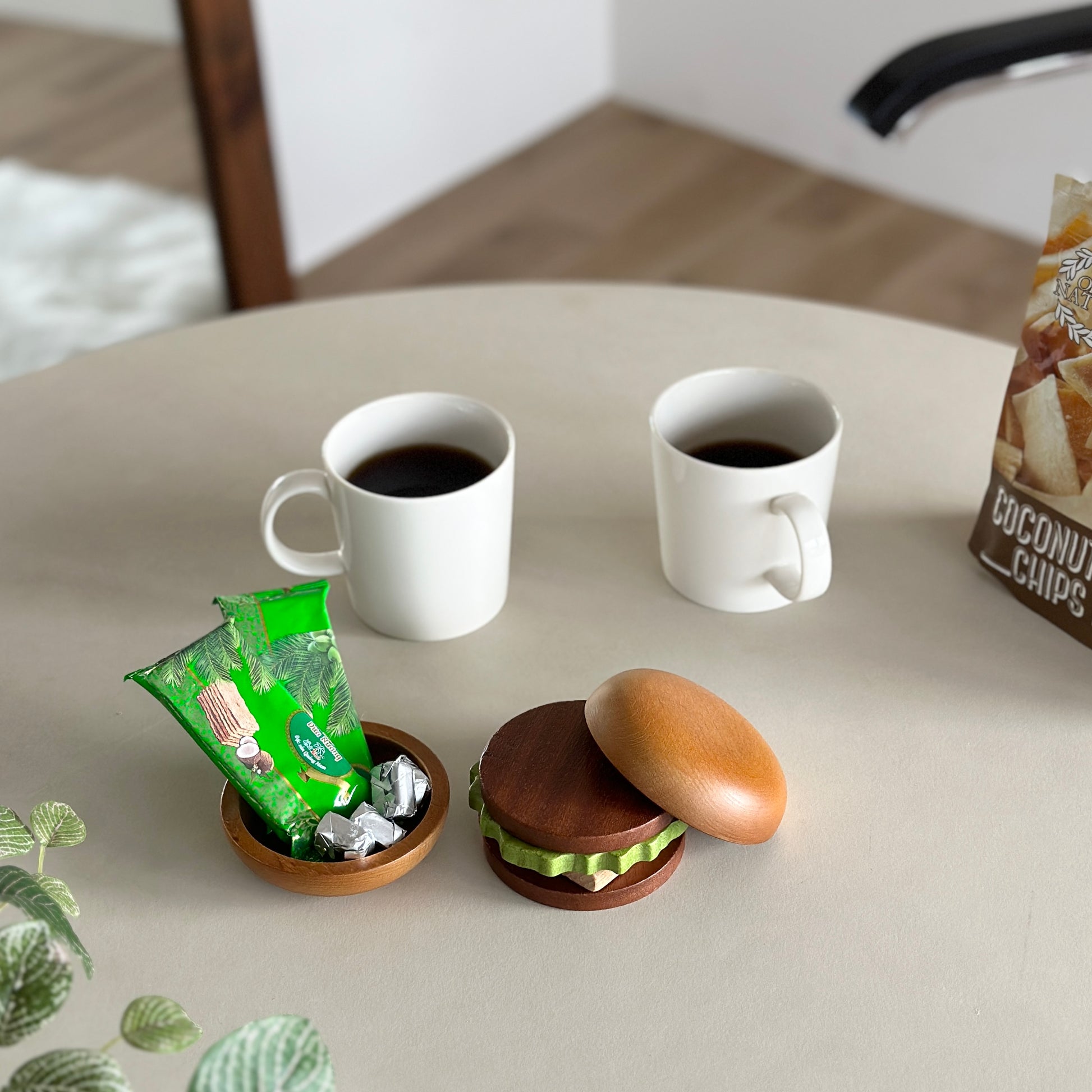 ハンバーガーデザインのコースターの周りにコーヒーが入った白のコップが二つ置かれてある
