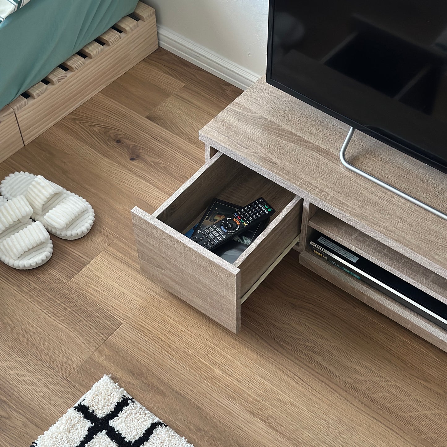 ホワイトオークのテレビボードの引き出し収納にテレビのリモコンやDVDが入れられている