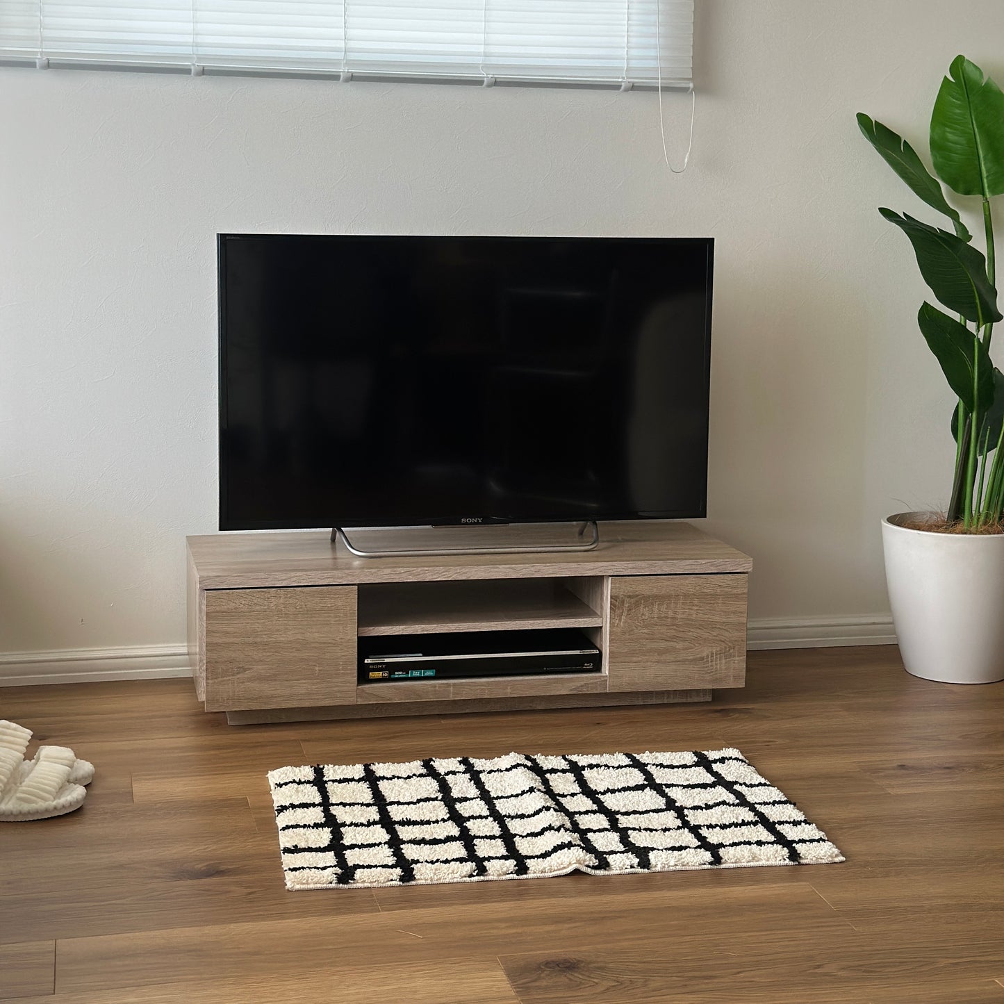 ホワイトオークのテレビボードの前に白と黒のチェック柄のミニラグが敷かれてある