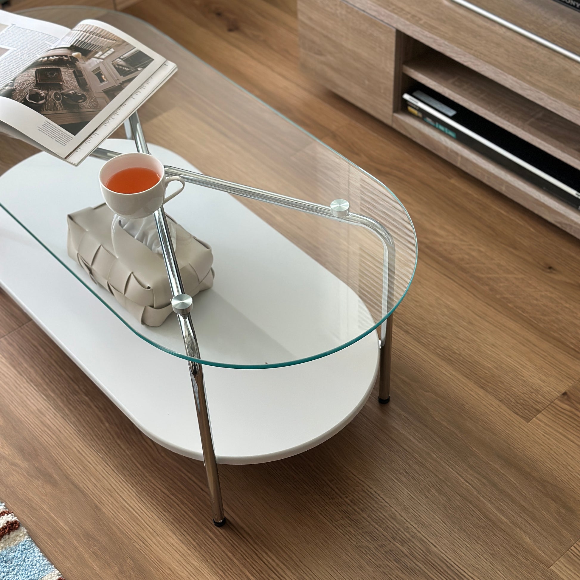 丸みのあるガラス天板のローテーブルの天板上にはコップと雑誌が置かれており、下の棚にはティッシュケースが置かれてある