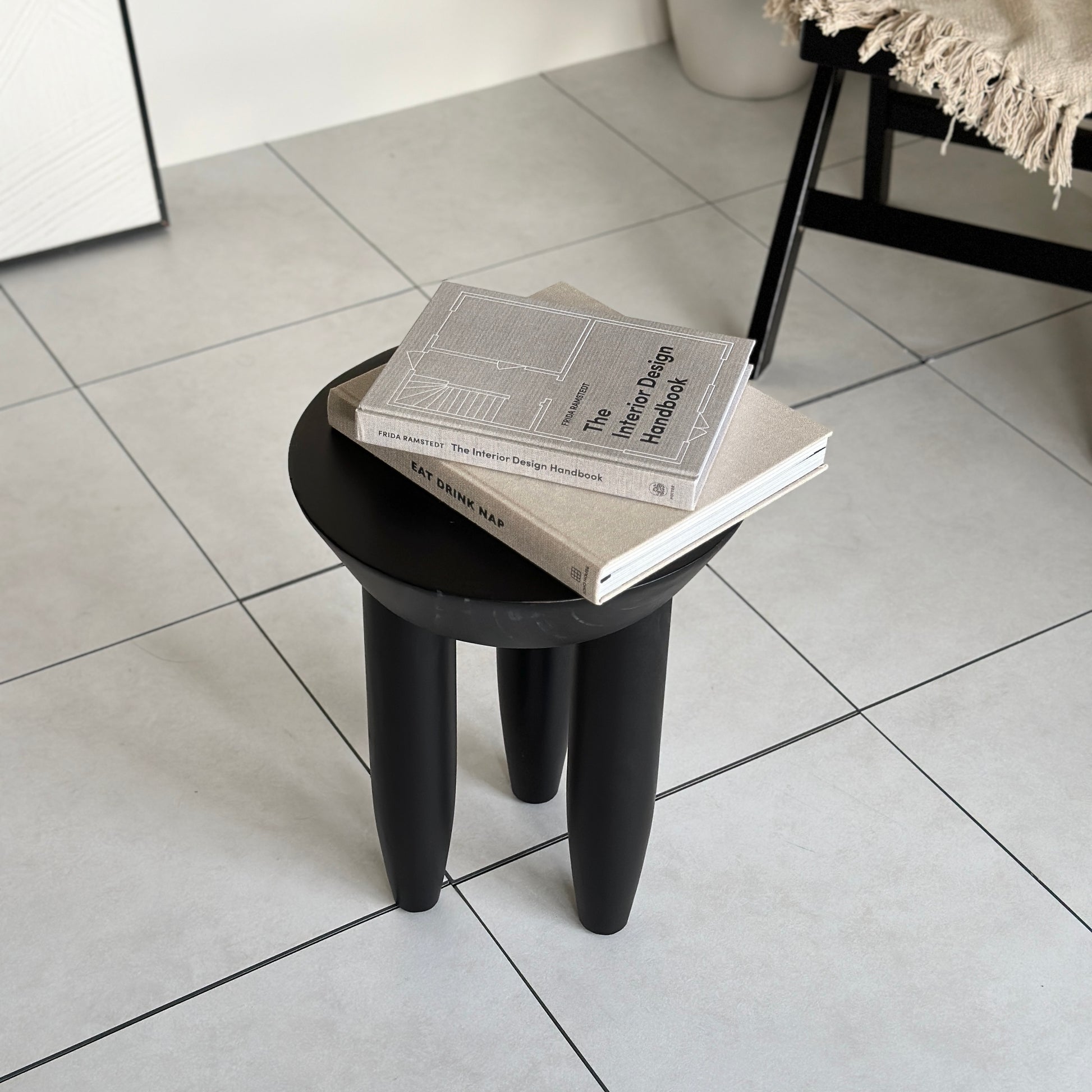本が2冊乗っているブラックの木製スツール
